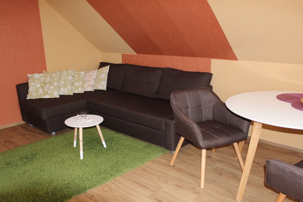You enter the newly furnished holiday apartment via a separate external staircase with an adjoining roof terrace and your own entrance.

In the living room there is a dining table with 2 chairs, a sofa bed and a smart TV as well as a radio. The bedroom has a double bed (160cm x 200cm) with nightstands and a wardrobe. The kitchen is equipped with a refrigerator, ceramic hob, sink, dishwasher, microwave, coffee machine, toaster, kettle, egg cooker, dishes and cutlery. A large shower, a toilet and a sink with a mirror, as well as a small hallway are also in the apartment.
A parking space under a carport is available. Two bicycles and internet connection can be used free of charge.
