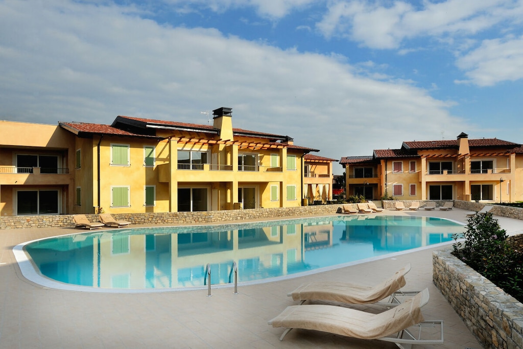 In the elegant and new residence "Le Corti Caterina", not far from the center of Desenzano del Garda and the lake, ground floor apartment for a holiday up to 6 people!
The apartment with free Wi-Fi internet connection welcomes guests with its bright living room with double sofa bed, flat screen TV, dining table with chairs, fully equipped kitchen with gas stove, fridge, freezer, dishwasher, oven, microwave, kettle, citrus juicer, coffee machine and toaster.
From the living room you can access the private garden, equipped with table and chairs for breakfast and outdoor meals.
The apartment continues with the master bedroom with double bed and large closets. The second bedroom with bunk bed and the bathroom with shower, sink, toilet and bidet complete the furnishings of this large and comfortable apartment, ideal for a comfortable stay on Lake Garda!
The apartment is also equipped with washing machine, iron and ironing board!
Guests of the apartment can conveniently park their car in the private garage inside the residence.
The shared pool is open from May 1st to September 30th.
With a small additional charge, possibility of providing a cot and a high chair.
Pets are not allowed.
Key collection/return at our office: Località Rovere 2, 25015, Desenzano del Garda, BS, (GPS: 45°27"29.6"N 10°30"57.1"E).
In accordance with the provisions of Italian law, we require the payment of a contribution for the sanitization and disinfection of the apartment upon registration.
CODICE CIR: 017092-CNI-00074