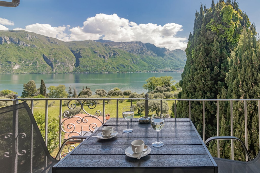 The beautifully furnished, spacious and bright apartment is located on the second floor of a building, accessible via a staircase, and features a terrace from which guests can enjoy a wonderful view of the lake and the surrounding mountains. The apartment opens onto a large and bright living room with a balcony overlooking the lake, complete with a Smart TV, a sofa and a dining table. The separate kitchen is equipped with all necessary cooking utensils, including an oven, a dishwasher, a kettle, a juicer and a toaster. The sleeping area features two spacious bedrooms, one with a queen-size bed and one with two single beds. A bathroom with a bathtub that can also be used as a shower completes the facilities.
Guests have at their disposal amenities such as washing machine, iron, fans, free Wi-Fi and heating.
*Guests benefit from an outdoor parking space inside the house.