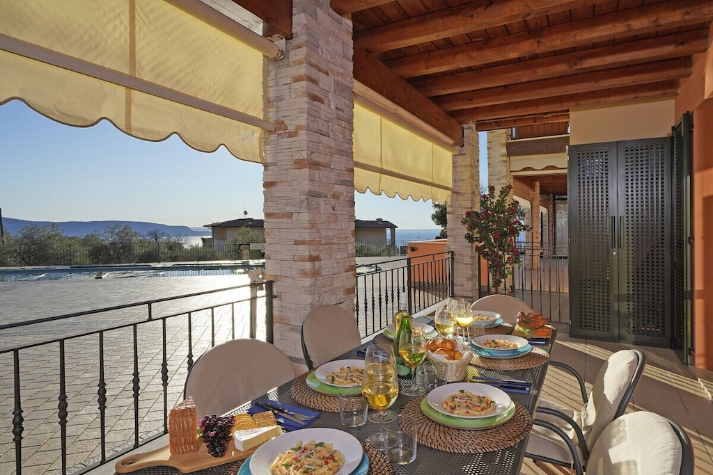 The apartment opens onto the large living room, furnished with a comfortable double sofa bed, Smart TV, dining table and a fully equipped kitchen complete with oven, microwave, dishwasher, kettle, juicer, American coffee machine and toaster. From the living area guests can access the large terrace overlooking the pool and the lake. The apartment further features two bedrooms: one with a queen size bed and Smart TV, the other with a bunk bed, an additional pull-out bed and a wardrobe. Both rooms overlook a private balcony with mountain and lake views. A bathroom with shower completes the facilities.

Guests have at their disposal amenities such as free Wi-Fi, air conditioning, heating, washing machine, iron and mosquito nets throughout the house.

Cots and high chairs are available upon request.

Guests benefit from a garage inside the house.

The shared swimming pool is open from June 1st to September 15th. A swimming cap might be required.