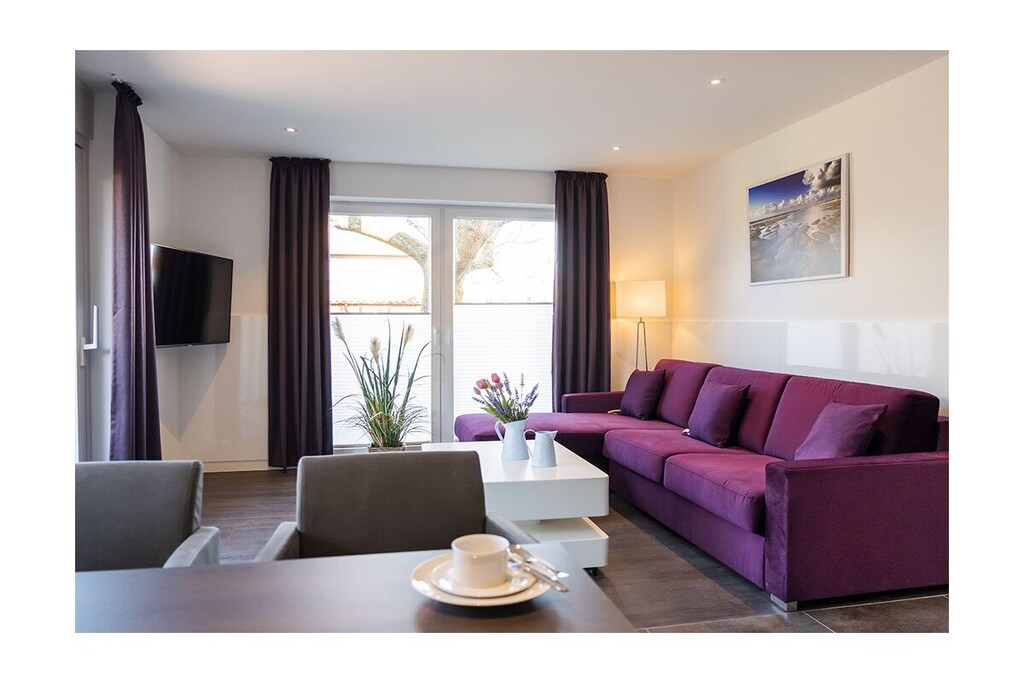 Luxury Apartment Norddeich Dream Pearl
Experience a luxurious holiday in Norddeich. This holiday apartment offers you an extraordinary flair. Completely renovated in 2019, the apartment not only offers every comfort that guests could wish for for a pleasant stay, but also sets high standards with its luxurious furnishings.
The holiday home is in a prime location in the heart of Norddeich. Only a few meters separate the holiday guest from the dike and the beach behind it. It is also only a few minutes' walk to the center with its various leisure activities and shopping opportunities. Nevertheless, guests can look forward to a quiet location in which absolute relaxation from everyday life is possible.
The holiday apartment
The heart of the apartment is the spacious living room. The very elegant sofa is a great place to relax. Perfect entertainment is guaranteed thanks to the large wall-mounted TV. The room has an exquisite flair not least thanks to the high-quality modern vinyl floor. The trendy LED lighting also provides pleasant, warm light. As in the rest of the apartment, this is built into the suspended ceiling construction. If required, the lighting can be dimmed individually.
All windows in the room as well as the patio lift-sliding door are equipped with fly screens and electrically operated roller blinds, and there are also elegant pleated blinds on two French doors.
The kitchen is also completely new, in addition to high-quality kitchen appliances, a back wall with 2 seats for the dining area has been integrated, and there are 2 very comfortable kitchen chairs on castors to match. In the bedroom there is a new 1.80m x 2.00m box spring bed with an additional back wall panel structure, in which an LED light strip is built behind the headboard and on the sides. In addition to the usual bedside lamps, the bed has two high-quality gooseneck reading lamps. There is also a sufficient