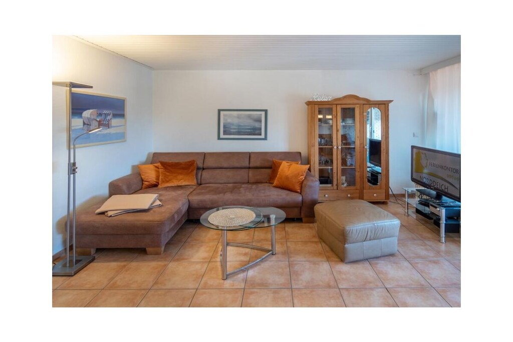 Holiday apartment Dörperweg 3, Norddeich, sea view
Apartment 17, 3rd floorThis beautiful holiday apartment is in a wonderfully central location in Norddeich, just a few steps behind the dike. Due to its location on the top floor of a well-kept apartment building, guests can enjoy a side view of the sea.
The pretty little apartment has been furnished with great attention to detail and a sense of functionality. The heart of the apartment is the combined living and dining area, which invites you to spend many pleasant hours. The living area has been equipped with a comfortable corner sofa (with sleeping function) and a TV corner, so that entertainment is guaranteed even on rainy days. The kitchen is practically furnished and has everything you need for cooking together. In addition to the dishes and cutlery, this includes amenities such as a stove with oven, a coffee machine, a refrigerator, a microwave, a dishwasher integrated into the kitchenette, a toaster and an egg cooker. The cozy dining area offers space for four people.
The highlight of the sea view apartment is the balcony adjacent to the living room. This has been converted into a glazed winter garden. This means you can enjoy the wonderful North Sea panorama even in winter. When the weather is nice, the winter garden can be opened so that guests can fully enjoy the pleasant climate. Thanks to the south-west orientation, you can enjoy the wonderful sea view from the balcony/winter garden. A comfortable seating area for four people ensures comfort.
The guest apartment has a small, cozy bedroom, which is equipped with two 90 x 200 cm single beds. The wardrobe offers enough space for the wardrobe. In addition, jackets and coats can also be stored in a second closet in the hallway.
The beautifully designed small bathroom has a shower, a toilet and a washbasin combination with a large