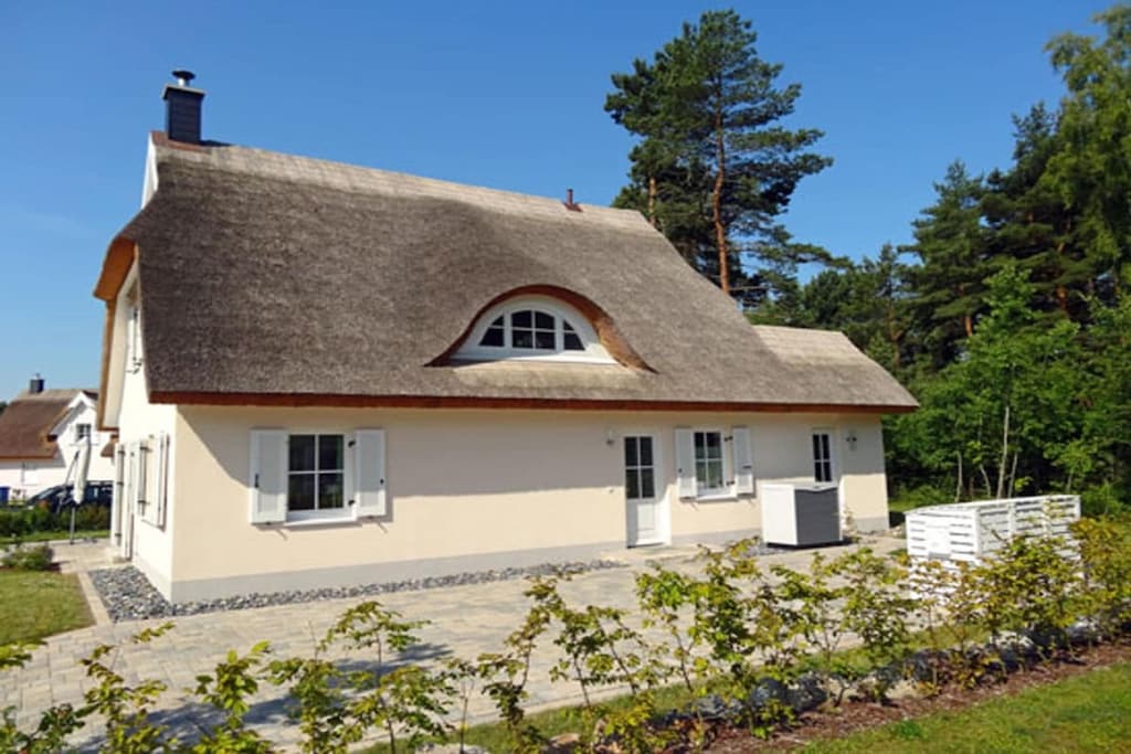 Glowe resort, over 2 floors, quiet location, approx. 400 m to the sandy beach (Baltic Sea), approx. 1 km to the Bodden, exclusive forest edge property 780sqm with spacious thatched roof house, 4 bedrooms for 8 people, sauna with infrared heater, fireplace, 2 bathrooms
The property borders a small forest to the north. House newly built in December 2013, family-friendly thatched roof house, in a new thatched roof settlement approx. 5 minutes walk to the beautiful beach, children's playground in the immediate vicinity, 1 large terrace south and west side with 2 separate patio doors, attractive garden furniture, 4 loungers, 1 beach chair, 1 large parasol, grill, spacious lawn area, ideal for children. Living space approx. 130sqm, of which bright, spaciously furnished living-dining area 47sqm with TV and Blue Ray. WiFi is available. 4 bedrooms on the upper floor, 3 of which have double beds (1 double bed 180 x 200) / 2 double beds (160 x 200) always single mattresses, 1 room with separate beds (90 x 200) all bedrooms are equipped with a TV.
The house impresses with its size, brightness and comfort with the expansive open space and the pretty shutters on both floors. 3 parking spaces available directly at the house. The beds are suitable for allergy sufferers. The open kitchen is equipped with a dishwasher, stove with ceramic hob, extractor hood, microwave, coffee machine, toaster, kettle and a large refrigerator with a spacious freezer compartment - ideal for larger catches of fish. The bathroom on the upper floor includes a hairdryer, a large LED mirror, radio, an electric towel dryer, bathtub and shower. The bathroom on the ground floor is also equipped with an LED mirror, radio and a separate floor-level shower in the sauna area. The uniqueness is rounded off by the integrated extension, where utensils for the outdoor area are stored, accessible from the inside and via a separate side entrance door. A weatherproof ti