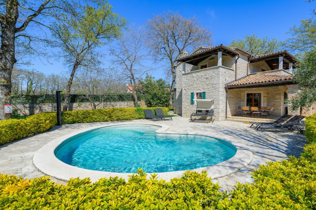 Villa Elaya offers an enchanting retreat in the picturesque village of Banki in the Tinjan region of Istria. Surrounded by lush oak trees, the villa offers a peaceful and relaxing ambiance, perfect for families or couples seeking a quiet retreat.
The blend of rustic charm and modern amenities, combined with the idyllic surroundings, makes it the perfect choice for a peaceful holiday. Whether relaxing by the pool, dining al fresco, or exploring the stunning Istrian landscape, guests are sure to create lasting memories at this exquisite property.
Interior Layout of Villa Elaya:
Ground Floor:
Open-plan living and dining area, seamlessly connected to a fully equipped kitchen.
Direct access to a covered terrace overlooking the sparkling pool.
A family room with:
A comfortable double bed.
A pull-out sofa bed, ideal for additional guests.
A bathroom with a shower.
A utility room with a washing machine.
First Floor:
Two elegant double bedrooms, each with its own balcony, furnished with a small table and two chairs for morning coffee or evening relaxation.
One bedroom has an en-suite bathroom with a bathtub.
A second bathroom with a shower is conveniently located near the other bedroom.
Outdoor Amenities:
A large, fully fenced garden ensures privacy and security.
Pool area with sun loungers and an outdoor shower.
Barbecue area, perfect for al fresco dining.
On-site parking for two vehicles.