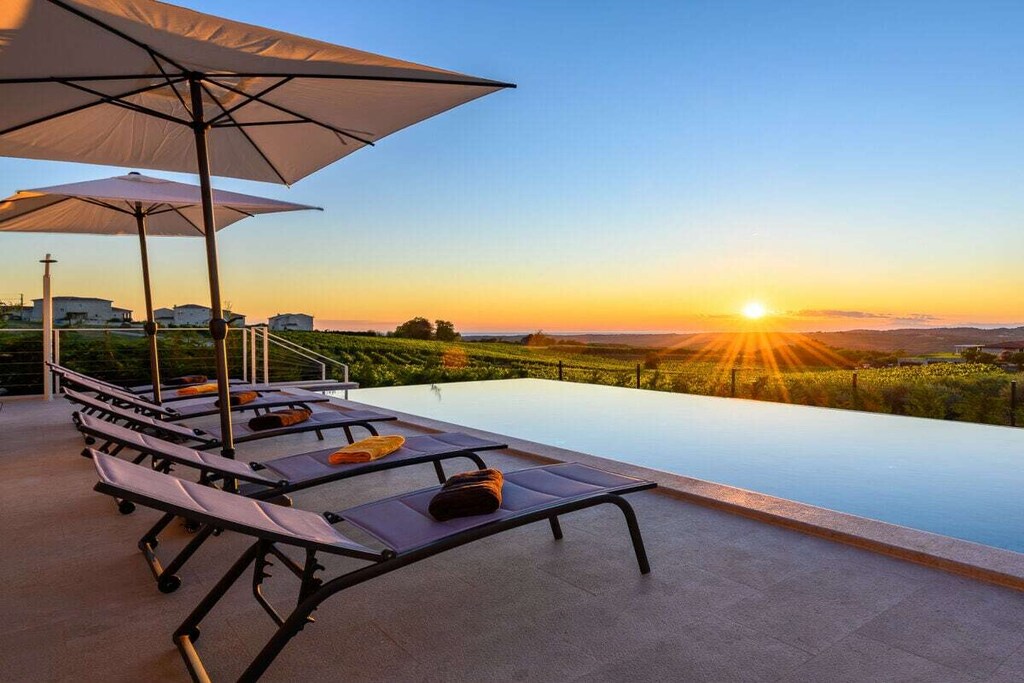 Nestled amidst the greenery of the ViÅ¾inada hills, overlooking vineyards and a beautiful sea view, lies the luxurious Villa Faloniga. It takes its name from a nearby natural spring that has provided life since ancient times.
This exquisite luxury holiday home near Bajkini features four elegant double bedrooms, each with its own en-suite bathroom, a spacious kitchen, and a dining area. The cozy living room, as well as the entire villa, is inspired by earthy colors and the beauty of nature, creating a uniquely relaxing atmosphereâ€”in connection with nature.
The infinity pool, which changes color in combination with the sun, sky, and clouds, adds a charming touch.
Come and fall in love with this villa near Bajkini, where you can enjoy the peace and beauty of nature.