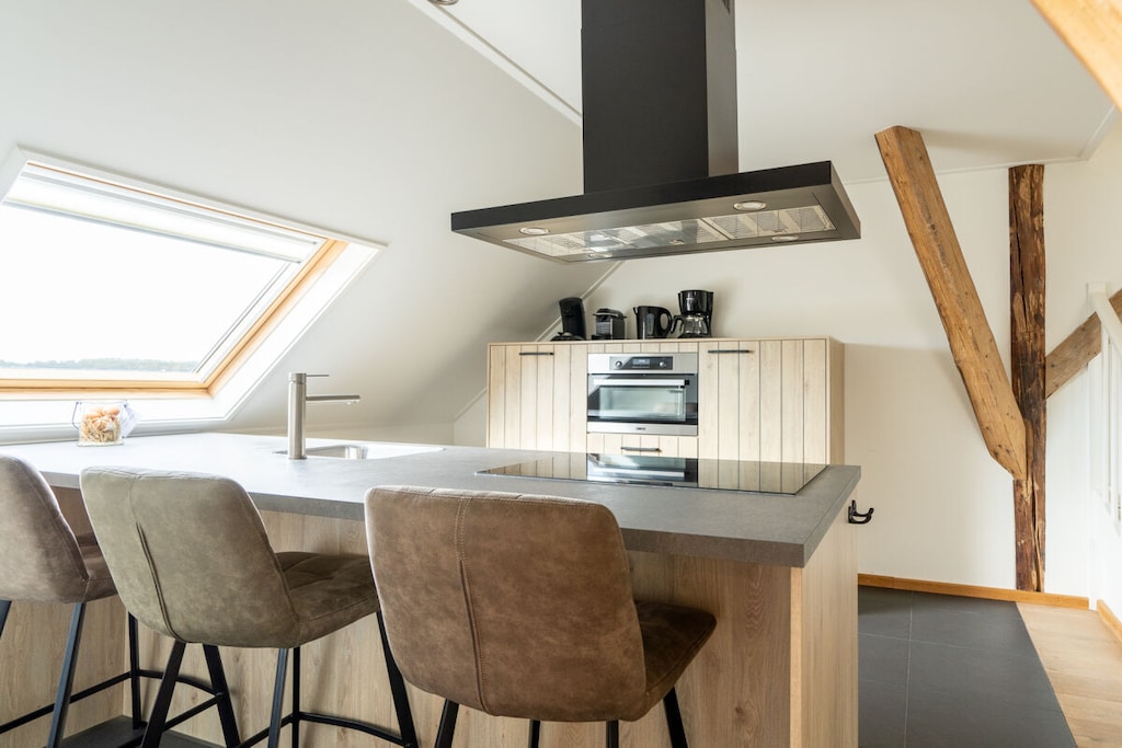 This apartment features two bedrooms on the ground floor, one of which is an en-suite bathroom. Also on the ground floor are a separate toilet and a second bathroom with a whirlpool tub, double vanity, and shower.

Upstairs, you'll find a spacious living room with beautiful, authentic features. It's a wonderful place to relax by the fireplace, a feeling enhanced by the lovely view outside. The spacious kitchen is fully equipped. There is also a separate toilet on this floor.

A fixed staircase leads to the mezzanine, which can accommodate two single beds (90 x 200 cm).