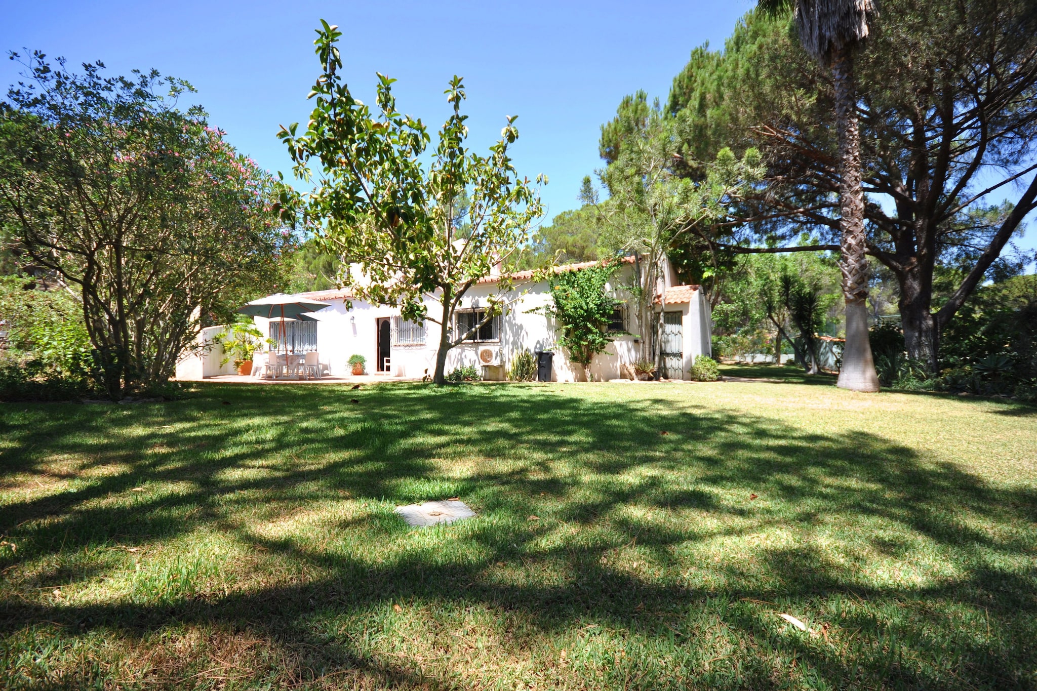 Comfortable & spacious, 4 bedroom traditional Villa with feature pine beam ceilings, terracotta tiled floors and open fire. Set in the Ria Formosa National Park with 4 acres of mature gardens which includes an orchard, the property boasts a large swimming pool on its own very large patio area, acrylic Tennis court and three hole golf green. This feature includes an all-weather three hole putting/chipping green with fringe surround and three nylon tee surfaces set at different elevations around it and Huxley Rotanet for practice of full irons and woods shots off a 4th Tee. The property is located within an area known as 'The Golden Triangle' (between Almancil, Quinta do Lago and Vale do Lobo) and is convenient for the exclusive sports and shopping facilities of Quinta do Lago (2 miles) and Vale do Lobo (3 miles) with its additional golf, tennis and beach restaurants and the town of Almancil (2 miles).
All these features make this property ideal both for families and golf enthusiasts.
The accommodation consists of:
- Fully fitted kitchen
- Living room
- dining room
- 1 en-suite bedroom with double bed
- 1 en-suite bedroom with twin beds (can be put together)
- 2 Twin bedrooms (one of which also has a sofa bed which can convert to a third full size single bed and a private patio)
- 3 bathrooms (2 en-suite)
Features:
- Large Private pool
- Large private gardens with orchard parking
- Garden furniture (table, chairs, sun loungers and parasol)
- BBQ
- Microwave
- Washing machine
- Dishwasher
- Satellite TV
- DVD
- Wi-Fi Internet
- Air conditioning
- Tennis court
- 3 hole golf green
About Belvilla
When you stay in a Belvilla home, you can rest assured of a unique holiday home in ideal surroundings at an attractive price. The portfolio of accommodations consists of more than 40,000-holiday homes in 20 European countries. Interested in a weekend getaway, a summer or winter sports holiday or simply a short break? Do you prefer the coast, the countryside or the mountains? Whatever your preference, there is a Belvilla home to meet your needs, from a cosy gîte for two to a castle big enough for the entire family, from an apartment in the heart of Rome to a cabin in the middle of nowhere, from a simple tree house to a luxury dream villa and from close to home to the other side of Europe.
A Belvilla home gives you the freedom to enjoy breakfast in your pyjamas or continue a good conversation into the morning hours without having to worry about the bar's closing time. Prepare gourmet meals with fresh local ingredients in your own kitchen and take advantage of having your own swimming pool to do as many cannonballs as you want! In other words, you can enjoy complete privacy in your home away from home.