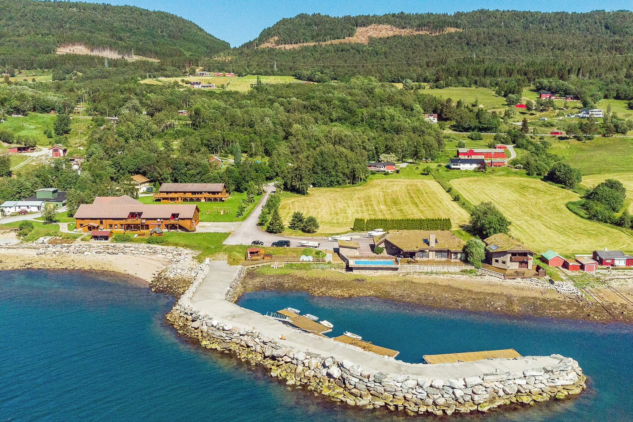 Enjoy a luxury holiday right by the sea, surrounded by magnificent fjord and mountain scenery. If you rent 88280 + 28041 + 88205 + 18869 you will in total have room for 41 people in the same place, 200 meters apart. A double door connects 28041 and 28042. There is a focus on top quality throughout the whole house. From the 30 m² large balcony, enjoy the panoramic view like on a cruise ship of the fjord and the mountains behind. The back wall of the balcony is all glass, giving you the same view inside the living room. In addition there is outdoors communal space for playing football, a communal terrace with a beach, covered outdoors grill with bar, pavilion and sun chairs. From 01/06 to 01/09, the swimming pool, is open from 12.00 18.00 every day. It is 50 m² and heated to 24 / 28 Celsius. The beach is sheltered by a large private pier, great for fishing. Several boats for rent. Book boats, canoes and kayaks at the same time as you book the house. The boats are located in a private harbour by the fjord. The fjord has plenty of fish, lobster and crabs.