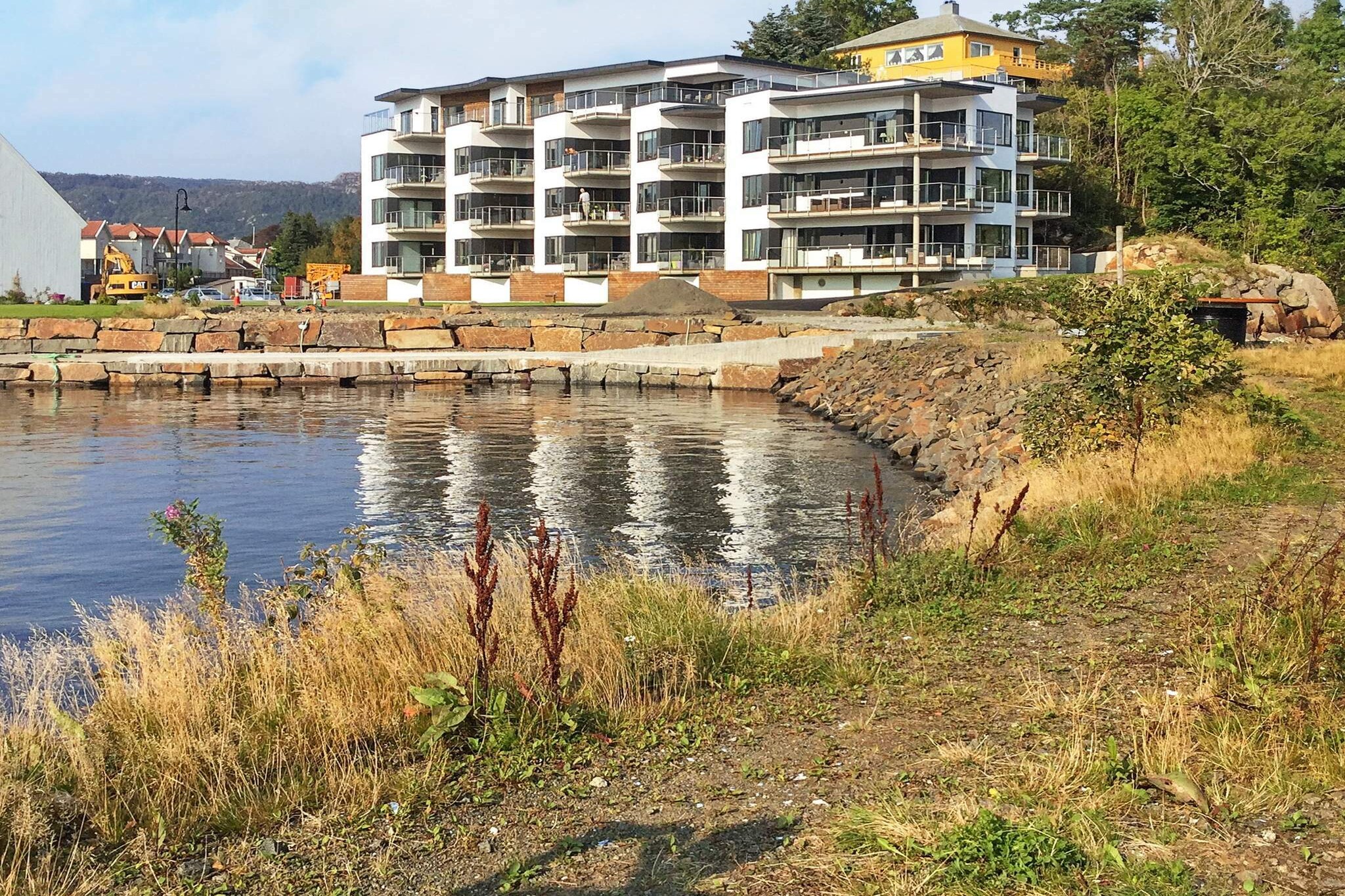 Modern, well-equipped holiday apartment with good facilities right by the fjord in Farsund. Great fjord view, lovely terrace with superstructure. Proximity to town and nature. This bright and modern holiday apartment offers a great view from the terrace to both the fjord, pier, and nearby beach area. The apartment is on the ground floor with an entrance at the back of the building, which is from 2016. Both the building and the furnishings are modern, and the apartment has a good room distribution. Two bedrooms, both with a double bed that can be separated into two single beds. Further down in the entrance hall entrance to larger bathroom with toilet, sink and shower cubicle as well as washing machine shielded part. Furthermore, there is an entrance to an additional toilet with hand basin. In end of the entrance hall entrance to a large living room with an open kitchen with dining table. In the living room, there is a bed for 2 people. Large windows provides good light and a nice view of the fjord, and from the living room there is an exit to nice terrace. The apartment has water-borne underfloor heating in all rooms. The holiday apartment is located in a residential area with several new buildings right next to it the fjord, only 50 m to the wharf. The center of Farsund is only 500 m away with restaurants and a bustling life in the summer months. Nearest grocery store is 200 m from the apartment. Farsund and the surrounding area offer rich nature experiences both along the coast, in the archipelago and further inland the country. There are parking options all year round.