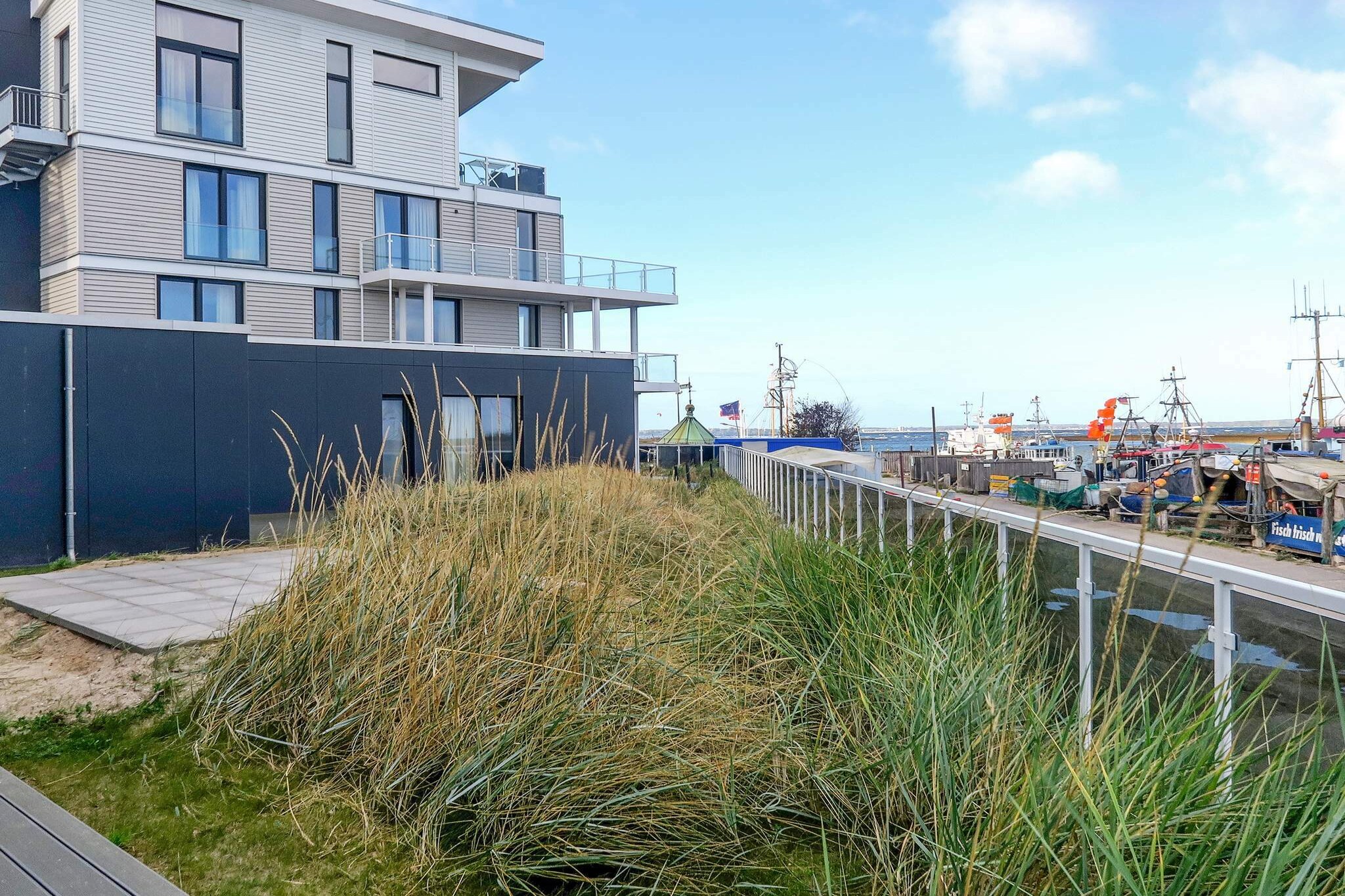 Step into a holiday home where space, comfort, and a touch of luxury come together with the Baltic Sea right at your doorstep. This modern ground-floor apartment offers not just a place to stay, but a retreat where the whole family—or a group of friends—can truly unwind while enjoying stunning marina views. The apartment is thoughtfully designed with a bright kitchen, dining, and living area that opens directly onto the terrace. Gather here for meals, games, or simply to relax by the flickering bioethanol fireplace. With four cosy bedrooms featuring double beds, an additional bedroom with two single beds, and a sofa bed for extra guests, there’s room for everyone. Three bathrooms bring spa-like comfort to your holiday: enjoy a soothing sauna, a bubbly whirlpool, or indulge in a double rain shower with steam bath function. Underfloor heating keeps every space warm and inviting, while TVs in every bedroom (and the living room) along with a Blu-Ray player and sound system make entertainment effortless. For the foodies, the kitchen comes with a special treat—a wok hob—so you can cook up your favourite Asian-inspired dishes. Outside, the harbour and sandy beach are just steps away, with the nearby Bottsand headland offering both family-friendly and naturist sections. In summer, sailing boats and ships heading to or from the Kiel Canal paint a lively maritime scene. During the famous Kiel Week, you’ll have front-row seats to the world’s largest sailing event—binoculars provided. Families will love the newly designed promenade with playgrounds, and the activity centre with indoor play areas and black light mini golf—all free for DanCenter guests. A private parking space rounds out the experience, ensuring your stay is as easy as it is memorable. Here, wellness meets seaside charm—whether you’re soaking in the sauna, sharing meals on the terrace, or simply watching the sunset over the Baltic, this apartment makes every moment feel special.A refundable deposit might be charged closer to your check-in date. The security deposit ensures a smooth stay and covers any additional services or consumption charges.This deposit covers utilities consumed during your stay and any additional services that may be taken.The final amount will be adjusted based on actual meter readings, actual usage of extra services, and any remaining balance will be refunded within 21 days after checkout.This deposit simply acts as a prepayment for charges that you would anyways pay for, ensuring a seamless stay and check-out experience.