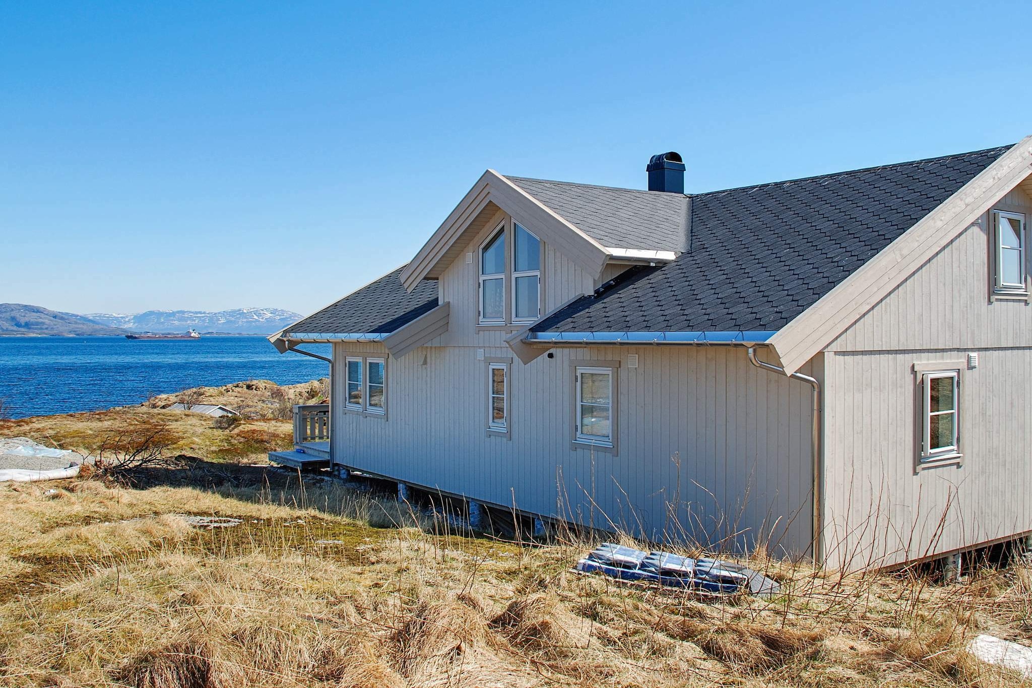 Comfortable and family-friendly holiday home with a great panoramic view to the charming coastal landscape of the Helgeland region. The cabin is located near the north coast of the island of Dønna and built in 2016, surrounded by beautiful hiking terrain and good fishing in the offshore sea. Leisure anglers can rent a boat for their trips. The house has two floors: On the ground floor kitchen / living area with dining area with wonderful sea views and two bedrooms each with double bed and bathroom with shower / WC, washing machine and dryer. The second floor contains two additional bedrooms, each included with two single beds, and a lounge area with PlayStation and TV (included with German channels) Make it comfortable with the whole family on cooler evenings in front of the blazing fire of the fireplace, viewable through large glass panel. The modern heat pump also contributes to a pleasant indoor climate. The room height is limited in the upper floor, max. 190 cm, on the sides of the sloping roof max. 110 cm high. The area is perfect for the active family who loves to spend time outdoors and enjoying the magnificent nature.  Note that this cabin is not available for fishing groups. The boat is available 01.05 – 30.09 A ferry is required to the house.