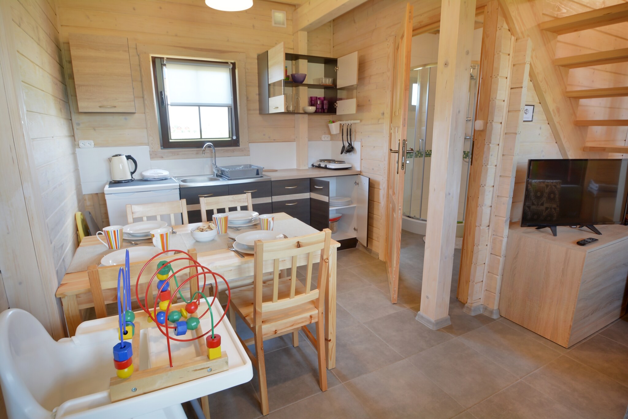 Ground floor: (open kitchen(hob, electric kettle, toaster, coffee machine, fridge), Living/diningroom(double sofa bed, TV(flatscreen, german television channels), dining table), bathroom(shower, washbasin, toilet))\n\nOn the 1st floor: (bedroom(single bed, double bed), bedroom(single bed, bunk bed))\n\nReception, Internet access, Table football, Table tennis, Sporting field(s), Indoor playroom, Play area, Lawn, cot, heating(electric), terrace(roofed), garden(shared with other guests, fenced, 2500 m2), garden furniture, sun loungers, BBQ(charcoal), parking, trampoline(shared with other guests), sand pit(shared with other guests), play equipment(shared with other guests), slide(shared with other guests), bicycles available, high chair, Garden shed, Swing set