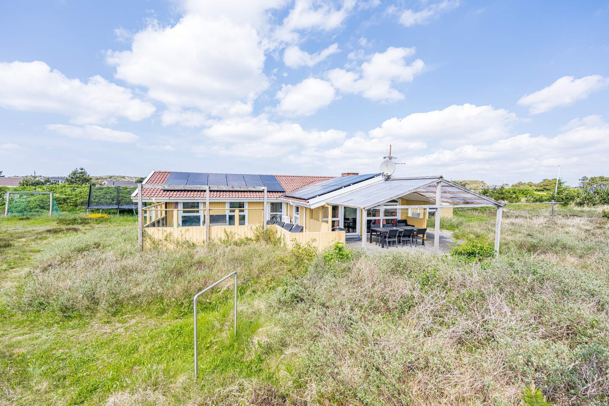 This beautiful “adventure house” is located on a magnificent natural property, adjacent to a heathland area. Inside, there is a large pool area with a swimming pool and whirlpool, as well as what is probably the largest sauna in Henne Strand. Outside, children will also find a swing, garden trampoline, and a small soccer field for fun and games. If you are looking for peace and relaxation, you can enjoy the beautiful view to the south over the heathland that stretches as far as Henne Mill. Sometimes you may be lucky enough to see deer from the vacation home, and early risers may also see fallow deer. The house has four bedrooms with box mattresses, a large bathroom with a washer and dryer, and a second bathroom with a shower. There is an open-plan kitchen/dining area with a view of the pool area so you can keep an eye on what's going on there. The vacation home and pool are heated by a heat pump. There is also a 25 m² covered terrace and a large, wind-protected terrace. Beautiful vacation home with pool in Henne Strand on the North Sea in Denmark. Final cleaning is already included in the rental price!