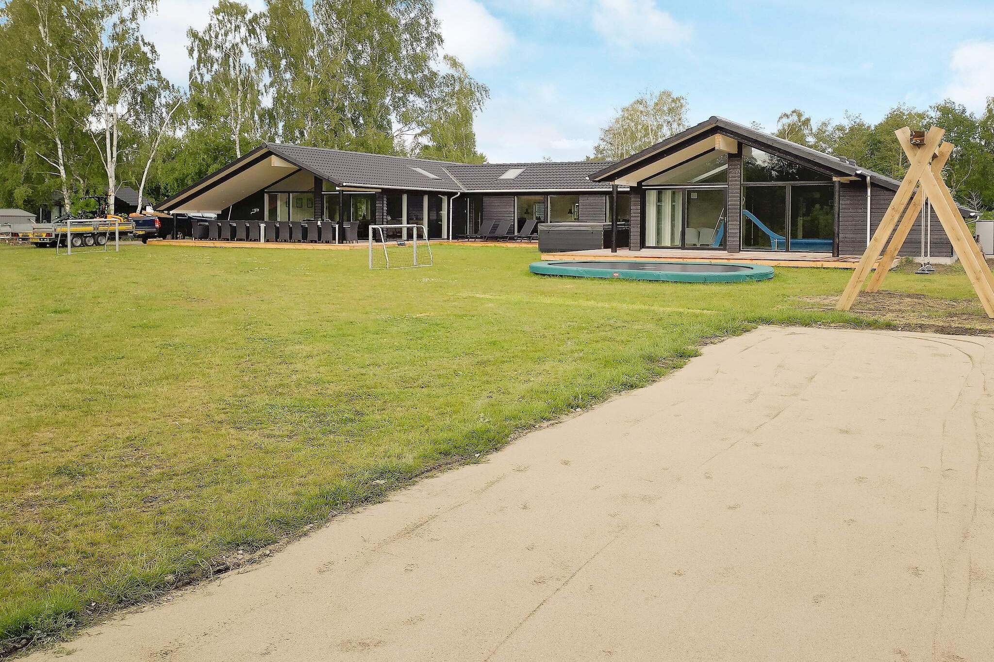 Just about 400 meters from Denmark's best bathing beach in Marielyst is this exclusive, unique large cottage with indoor pool, sauna, outdoor hot tub and an activity room. In the middle of the house is the meeting point of the house with large activity room with table tennis, table football, TV and PlayStation 5 and Nintendo Wii. The cozy fireplace room is with wood burning stove, TV and free, wireless internet. From both rooms there is access to three lovely terraces with plenty of space for sun, dining and with covered area on one. Here you will find the outdoor hot tub with room for 8 people, where you can sit all year and enjoy the heat watching the stars. In the large pool area you will also find a sauna and a bathroom. Many hours can be spent on fun, water games and trips down the slide, which are fun for both adults and children. There is also a cozy nook in the room. Large, bright kitchen / dining room with plenty of space and with a projector in the kitchen, so you can use the space for meetings. The kitchen is well equipped with i.a. microwave, 2 refrigerators, freezer, ceramic hobs, etc. In each of the two side wings there are separate bedrooms and bathrooms. The house has a total of 9 bedrooms and 2 alcoves. The 5 rooms are with double beds and 4 rooms have single beds. Cot and high chair available. In addition, there are three bathrooms with shower and a guest toilet. The well-equipped house has i.a. wood stove, air / water heat pump, free, wireless internet and TV with many channels such as German and Danish. In addition, a washer and dryer are available. Outdoors on the large plot of approx. 2,200 m2 there are 5 large wooden terraces with several sun and cozy nooks in several places, garden furniture, prams and barbecue. Cozy fireplace. For the little ones there is a swing and trampoline (used at your own risk / insurance). Not for rent to youth and artisan groups.