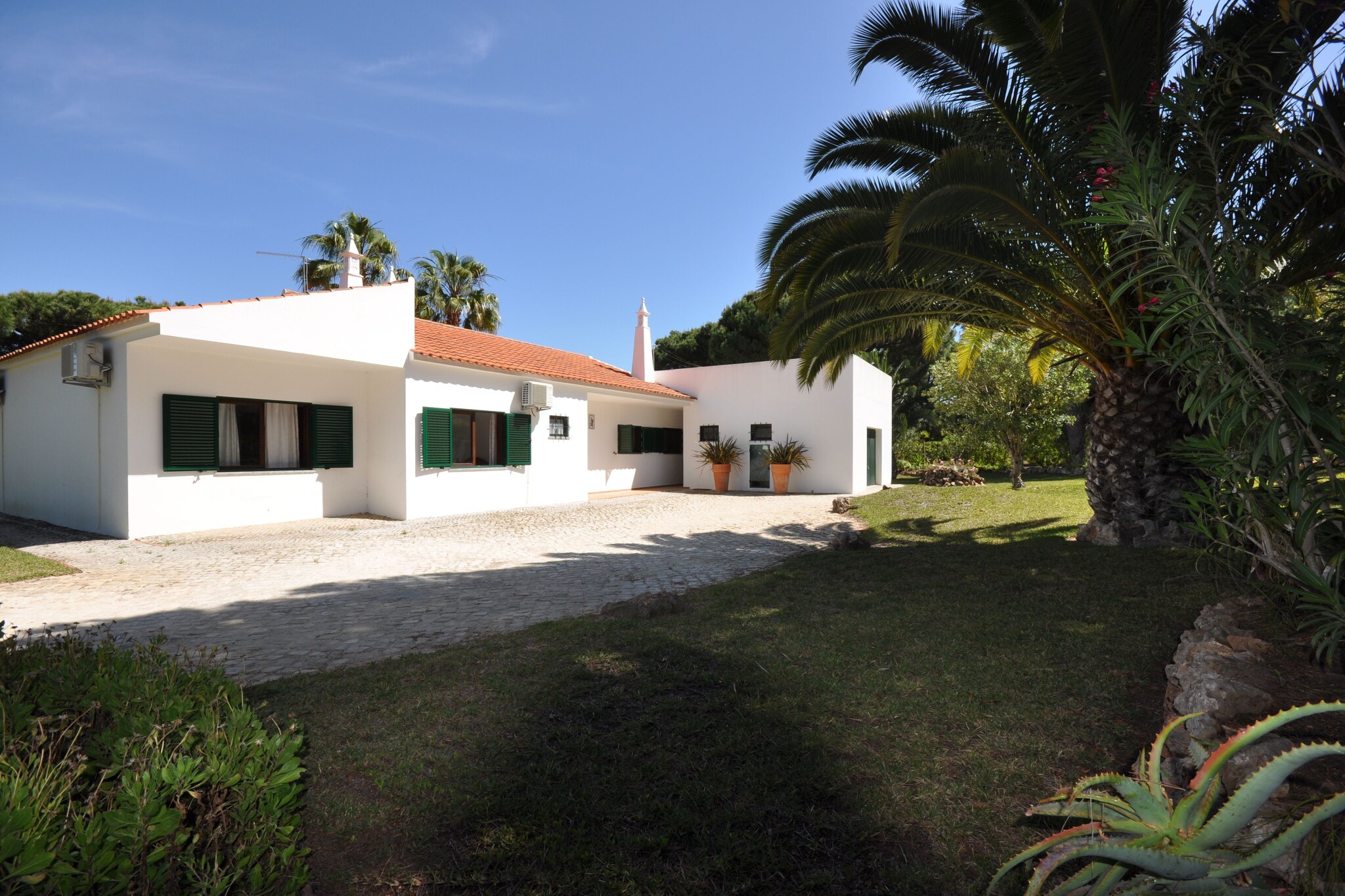 This spacious rustic villa is ideal for golfers or large families keen to enjoy everything Vilamoura offers and enjoy some lazy days by the poolside.
Standing in a cul-de-sac, this villa boasts a magnificent course practically on its doorstep, so will delight keen golfers, as well as please families looking for a spacious base in desirable, quiet surroundings.
Framed by beautiful, level gardens dotted with trees and largely laid to lawn, the highlight of the villa is its stunning pool area. Skirted by terraces offering plenty of space for everyone to relax, the kidney-shaped pool is generously sized and a perfect excuse to spend entire days basking in its waters and the gorgeous climate of the Algarve.
Patio doors from the terrace lead into the pleasant sitting-dining room, which in keeping with the other rooms, is simply but comfortably finished with natural wood furnishings, white walls and tiled floors. All the rooms are spacious and the well-equipped kitchen is complemented with a barbecue to encourage the outdoor lifestyle.
The attractions of Vilamoura, including its marina and beach are a short car journey away, and the Vilasol complex close by offers a choice of restaurants, bars and shops to enjoy.