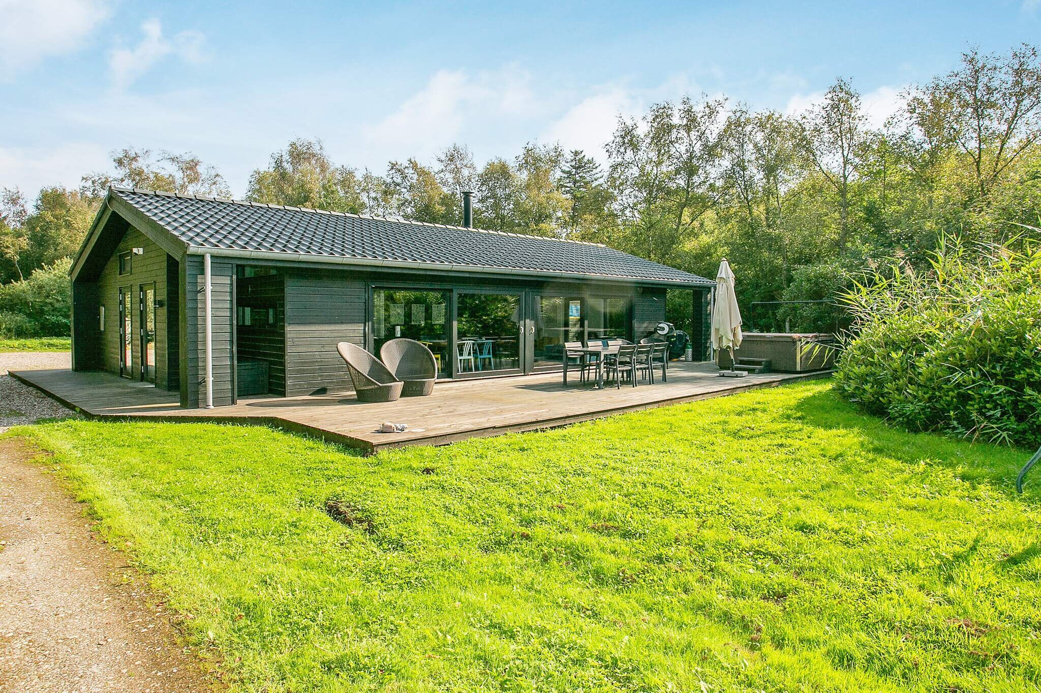 Tucked away in a quiet and scenic setting with beautiful views, this holiday home near Bogense offers plenty of space for relaxation and comfort. A highlight of the property is the inviting outdoor hot tub, perfect for unwinding in the fresh air while surrounded by nature.
The house is thoughtfully equipped for families or groups, featuring two bathrooms, a well-furnished open-plan living and dining area, and direct access to expansive terraces. Large windows fill the living room with light, where you’ll also find a cozy loft space (hems) with a TV and a panoramic view of the surrounding forest and hot tub below. The modern kitchen is fully equipped with everything you need to prepare meals, while three bright bedrooms provide ample storage and a restful night’s sleep. High-speed fiber internet (50/50 Mbit) makes it easy to stay connected or stream from your own providers.
For year-round comfort, the house includes both a climate-friendly heat pump and a wood-burning stove that adds extra warmth and charm on cooler evenings. Set on a large forest plot between Skåstrup Beach and Bogense, the location combines peaceful seclusion with easy access to the coast and nearby town amenities.
This property blends natural beauty, modern conveniences, and plenty of space to relax indoors and out. Please note: rental to youth groups is not permitted.