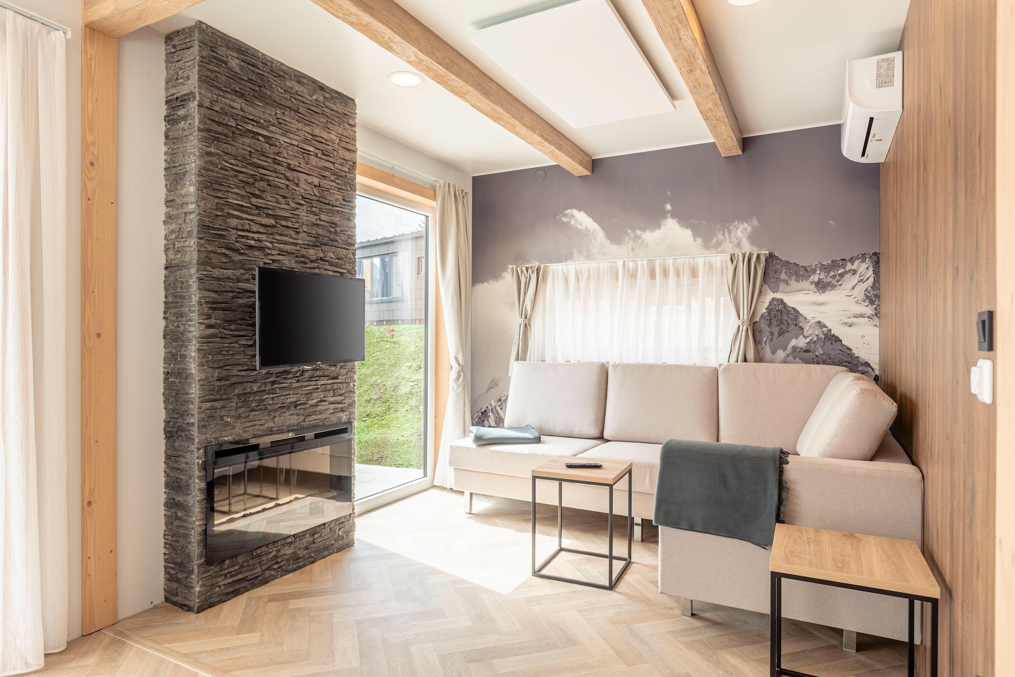 This modern, detached, single-storey chalet is located in the car-free resort Chalets & Glamping Nassfeld, which opened in May 2022. It is located at the forest edge near the small Vorhegg skiing area. The small centre of Kötschach-Mauthen is 650 m away.
The chalet is furnished in a modern and complete way. In the living room, you will find a TV and an electric fireplace. The open-plan kitchen with cooking island is equipped with an oven and dishwasher. The house features three bedrooms, one of which has a double bed, one two single beds and one a bunk bed. The bathroom features a shower and a toilet. For additional comfort, the chalet is equipped with air conditioning.
Outside, you will find an unfenced garden and a terrace with garden furniture. You can park your car in the central car park at the edge of the resort.
At Resort Chalets & Glamping Nassfeld, you can book various chalets for four to six people.