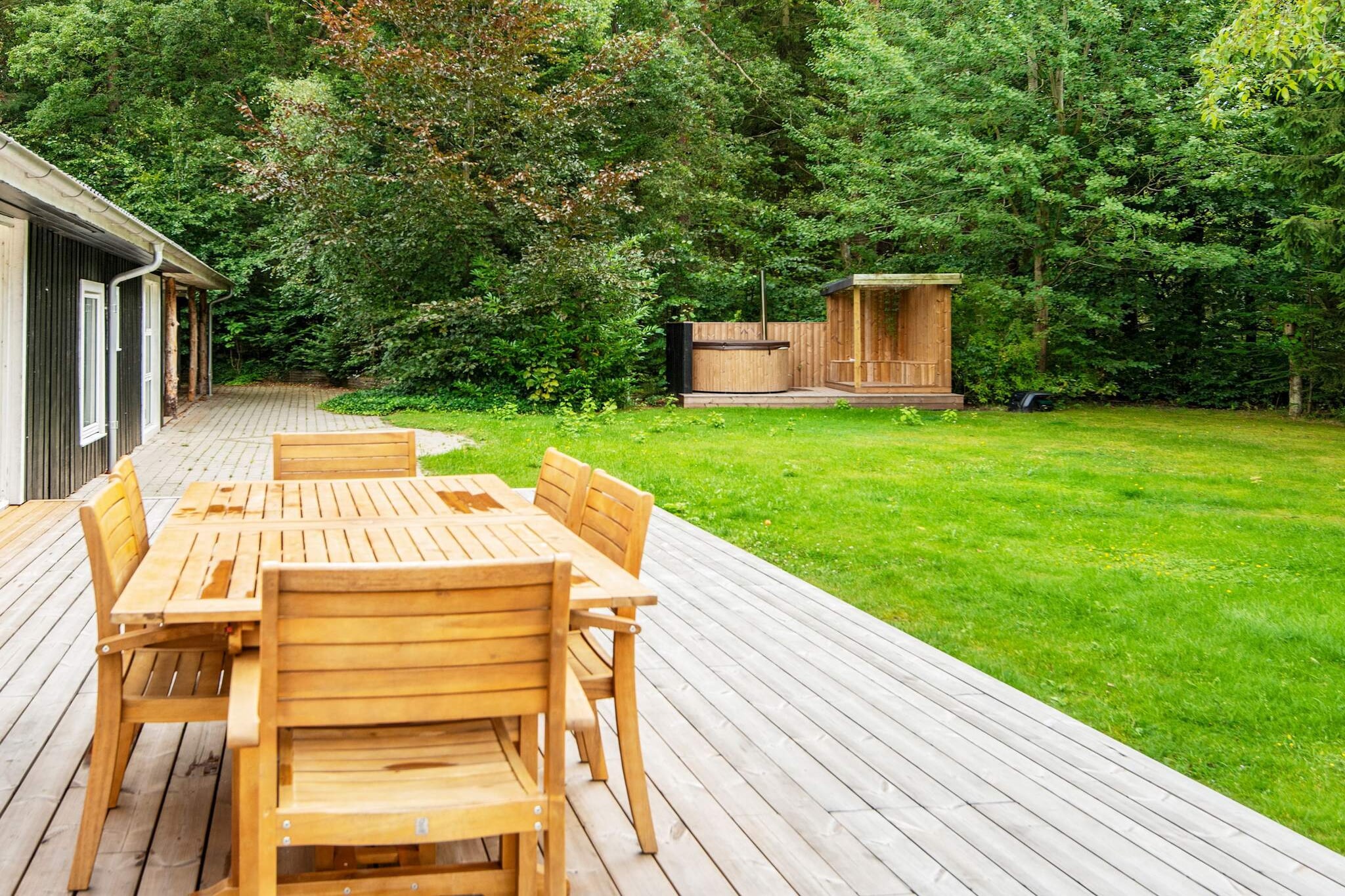 Renovated, beautiful summer house located in a quiet natural area by Mossø, at the end of a closed road. The house is situated on a large plot with a wilderness bath and several cozy nooks where children can hide and play in the garden, swing, or jump on the trampoline (used at your own risk/insurance). The wilderness bath is heated with firewood, which can be purchased at the house. The kitchen is open to the main living room, so everyone can enjoy themselves and play games or retreat to the smaller living room, which has a wood-burning stove. The house has five bedrooms with double beds, one of which also has a bunk bed. The house has two bathrooms, one with a toilet and shower (without a spa bath) and the other with a toilet.There are two living rooms, one of which has a TV and Bluetooth speaker. Both living rooms have wood-burning stoves, high chairs, and children's games. This unique house on the edge of the forest has seven garden doors, creating a seamless connection between indoor and outdoor living. In addition to games and play activities in the garden, there is a fire pit and an activity house with a table tennis table, darts, and various play equipment. The Gudenåen river runs alongside the small cottage area and can be reached 400 meters away, where there is a private green area, a boat dock, and swimming opportunities, as well as the option to privately rent the house's boat. In the area around the house, there are trails for hiking, forests for mountain biking, and good roads for road cycling. Not available for rental to youth groups or tradespeople.A refundable deposit might be charged closer to your check-in date. The security deposit ensures a smooth stay and covers any additional services or consumption charges.This deposit covers utilities consumed during your stay and any additional services that may be taken.The final amount will be adjusted based on actual meter readings, actual usage of extra services, and any remaining balance will be refunded within 21 days after checkout.This deposit simply acts as a prepayment for charges that you would anyways pay for, ensuring a seamless stay and check-out experience.