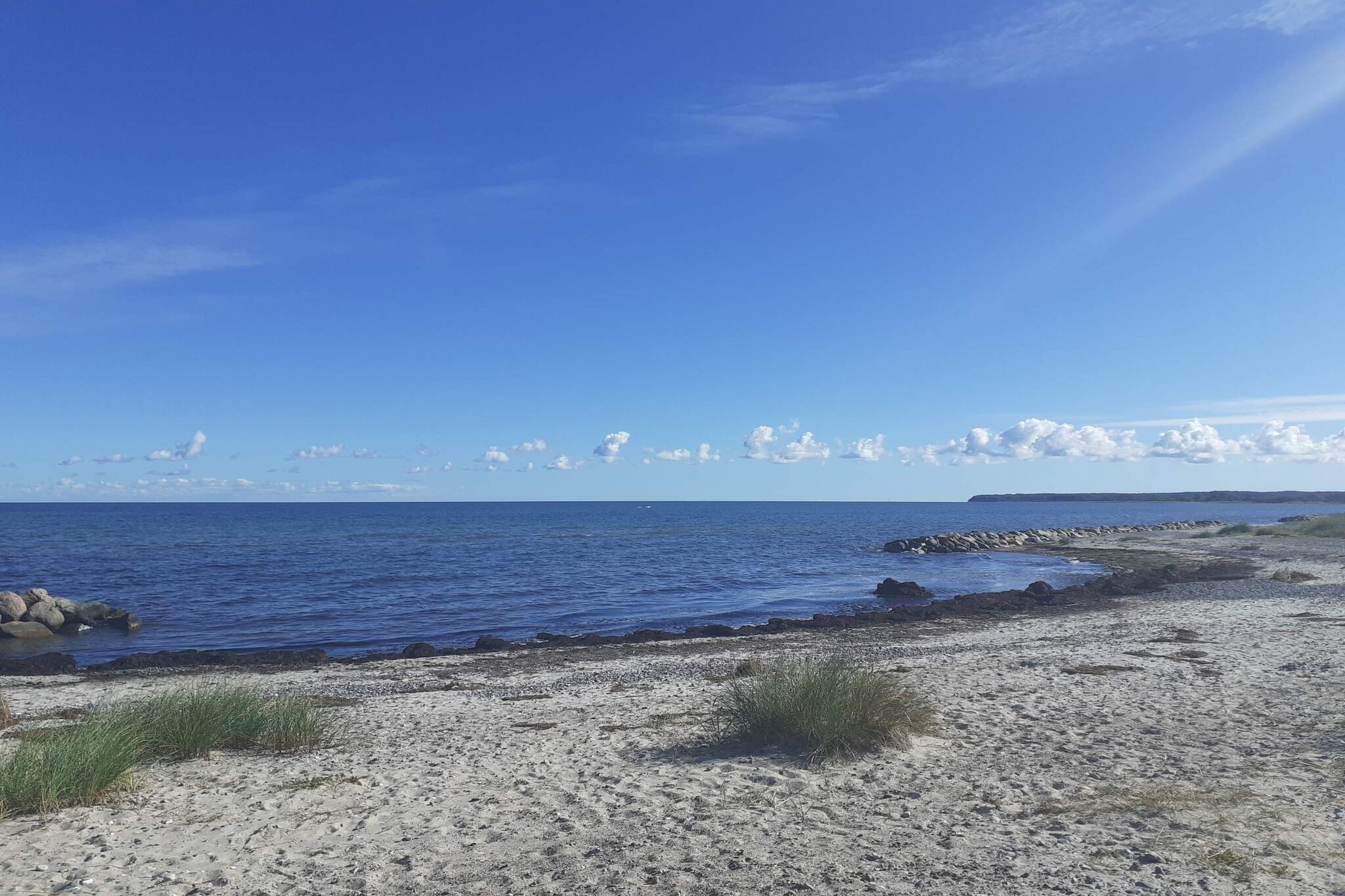 This charming holiday cottage offers 43 m2 of living space and an attractive location only about 2 km from the beautiful and child friendly beach at Ulvshale. The house is ideal for small families or couples who want a peaceful holiday close to the sea. Inside, the cottage features an open layout with kitchen, dining area, and living room combined into one bright space. From here, you have direct access to a covered terrace where you can relax outdoors in any weather. The house includes two bedrooms, one with a double bed and the other with a single bed. In the living room there is also a sofa bed that can accommodate two people, making the layout flexible for different family sizes. In addition to the main house, there is a cozy annex providing sleeping space for two more guests, giving larger families or groups of friends extra room and privacy. The terrace is a natural gathering spot for summer days, with a grill available so you can enjoy relaxed evenings together while appreciating the quiet surroundings. The area offers a wide range of activities and attractions. About 8 km away you will find an 18 hole golf course, while the charming town of Stege is located just 7 km from Ulvshale. Stege is well known for its harbor, local charm, and welcoming atmosphere, with a variety of restaurants, cafes, and shops to explore. Combined with the lovely sandy beach nearby, this holiday cottage makes a perfect base for both relaxation and active experiences on Møn. Please note The house is not rented out to youth groups.