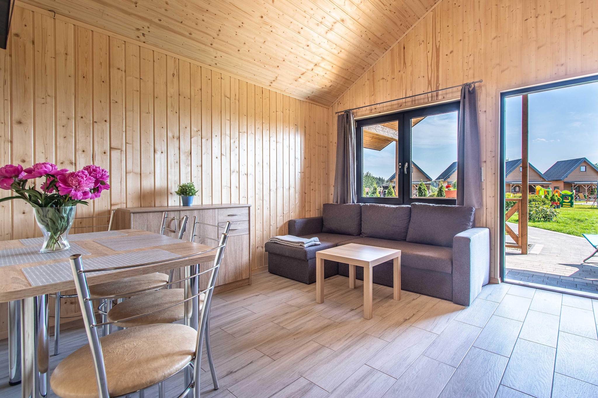 Ground floor: (open kitchen(dining table, hob(2 ring stoves, induction), boiling water tap, fridge-freezer), Living/bed room(double sofa bed, TV), bedroom(3-person bunk bed), bathroom(shower, toilet))\n\nPlay area, grill, heating(electric), terrace(roofed), garden furniture, parking, trampoline(shared with other guests)