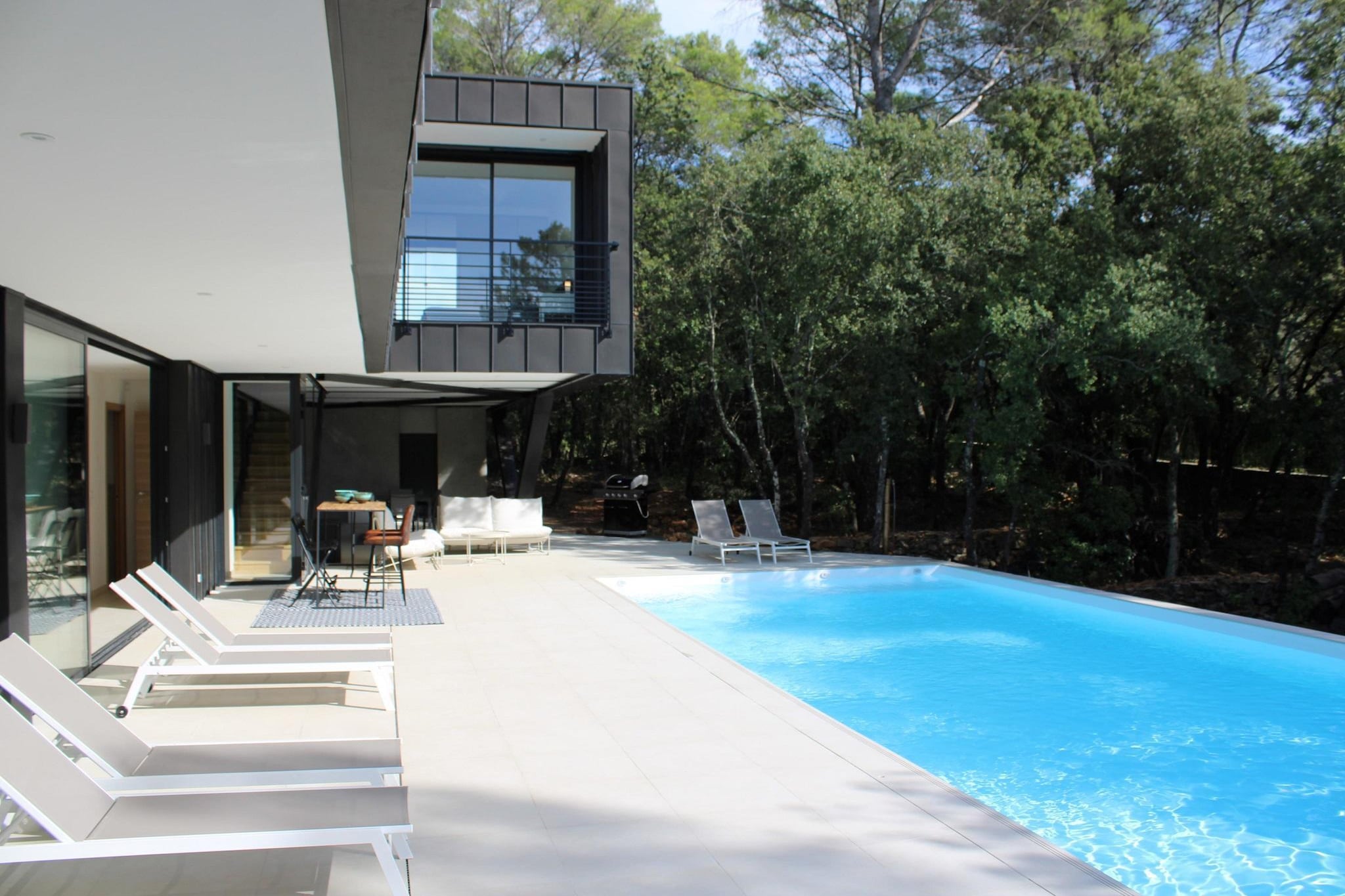 The highest part of the house was designed by the architect in such a way that you can look into the treetops from the bedrooms. The entire villa is air-conditioned and can comfortably accommodate families and groups of friends.
Villa La Canopée is a 20-minute walk from Chateau de Berne, one of the largest wine estates in the Var, with various wellness facilities, such as a sauna, massage and beauty treatments. Or what about a delicious lunch in the brasserie? Or fancy dining in a top restaurant? It's all possible!
The villa, modern and comfortable in design, is fully equipped. On the ground floor you will find the master bedroom with separate walk-in closet and private bathroom with walk-in shower. On the top floor there are 3 double rooms and the children's room. Since the children's room has 4 sleeping places, there is also room for 2 more small children; They will have to sleep together in the same room as the rest of the rooms have double beds. The other 2 bathrooms, one with a bath, can also be found on this floor.
Allowing the indoor space to flow seamlessly into the outdoor space - a trend that is reflected in many residential programs these days - is certainly applicable to this house. Through the large sliding windows, the living room with open kitchen flows into the covered terrace, where you will enjoy a beautiful swimming pool, a comfortable lounge set and a spacious dining table.
Switching on the swimming pool heating is always done on request and is only possible outside the summer months. During the months of July and August, the water itself has a wonderful temperature.