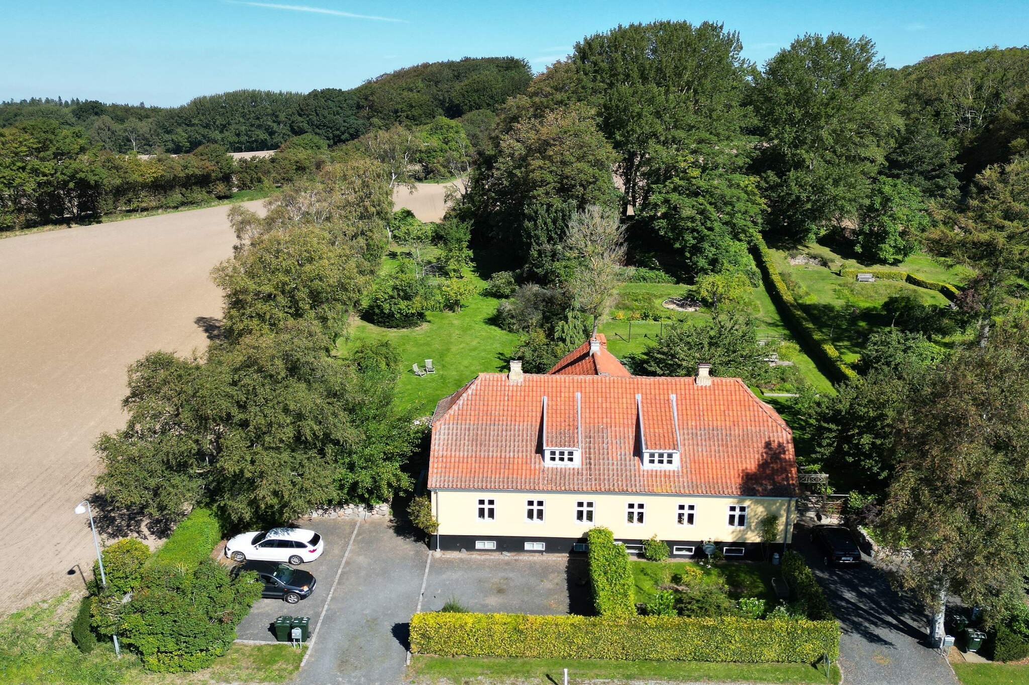 On the outskirts of the charming and historic castle town of Tranekær on North Langeland, you will find this summer house, which is half of a semi-detached house. The bright house has two floors, and from almost all the windows in the house there is a beautiful view of the landscape with open fields and wild horses.
On the ground floor, you will find a bathroom/toilet, a bedroom with a double bed, a kitchen, and two living rooms en suite, as well as access to the beautiful, hilly garden, where there is plenty of space to romp around or simply enjoy the sun, nature, and cozy get-togethers.
On the first floor, there are three bedrooms and a large landing with a large cot. The house has Wi-Fi and a TV with Chromecast, so you can stream your favorite programs. There is central heating with an oil furnace and a new wood-burning stove, so the house can be heated quickly all year round. The house has been continuously renovated and is bright and inviting.
The Archipelago Trail with its adventurous hiking routes passes right by the house. It is not far to the Medicinal Gardens, the Tickon land art park, Tranekær Castle with its café and restaurant, and horse riding on Icelandic horses (Stutteri Almindingen). Just 2 kilometers away, there is access to a beautiful and child-friendly beach (Åsø Strand) and excellent coastal fishing. Not available for rental to youth groups or construction crews.
The electricity consumption for the air-to-water heat pump is measured on a separate electrical panel located in the basement.
