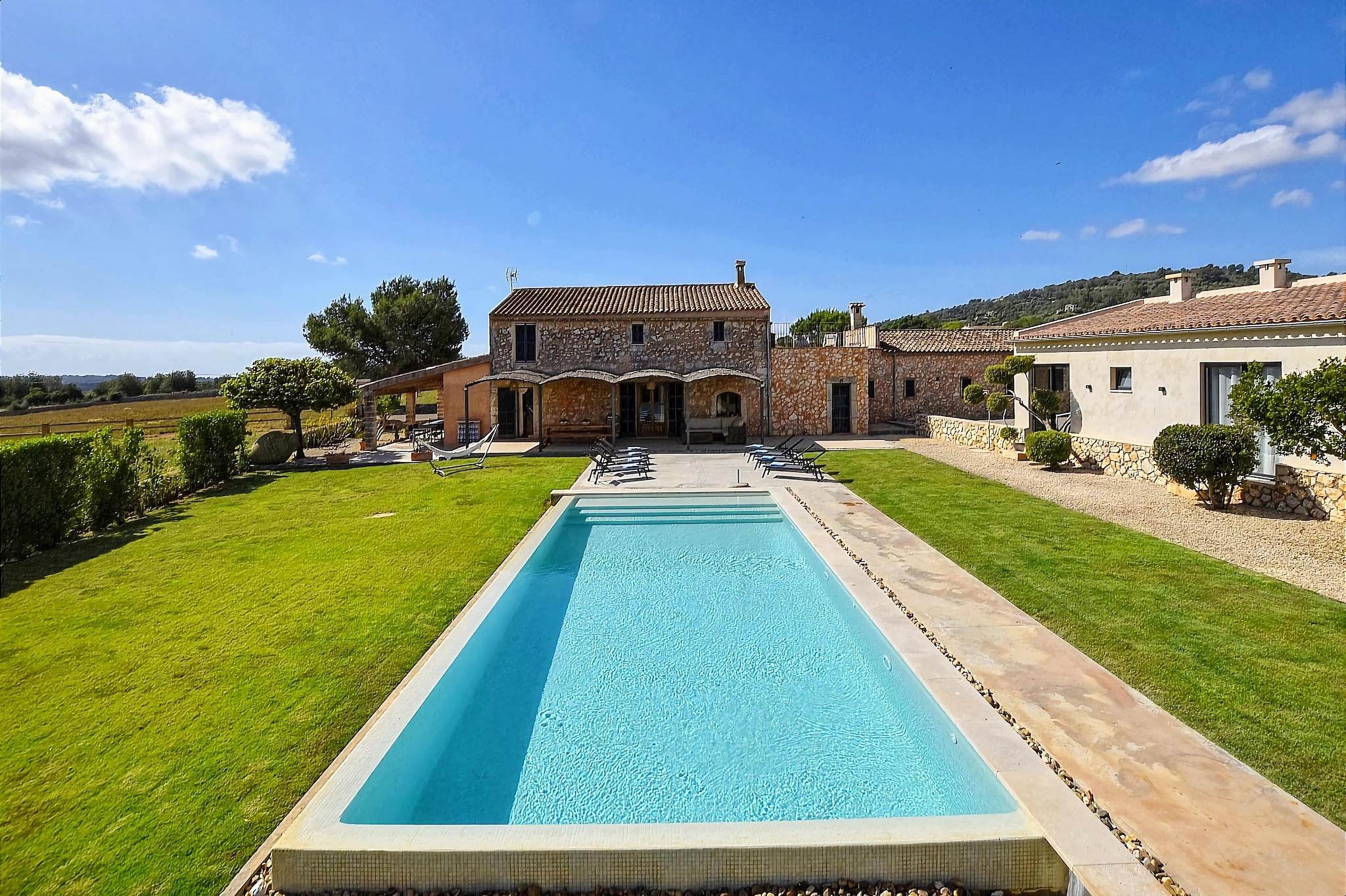 This modern, luxurious and incredibly stylishly furnished country house finca is located in the untouched idyllic countryside between Manacor and Son Carrio, just 10 minutes by car from the nearest beaches on the east coast such as Cala Millor or Sa Coma.
The finca is particularly suitable for families and groups and consists of a main house (220 m²) with four bedrooms and four bathrooms for a total of 8 guests and an adjacent guest house (80 m²) for a further 4 guests with two further bedrooms and the fifth bathroom. All bedrooms have air conditioning, five of them have a double bed and one of the rooms has two single beds.
The main house and apartment offer a private living room with a fireplace and a private kitchen equipped with a dishwasher. The outdoor area with the chill-out sofa corner and the surrounding partially covered terrace areas offers an incredible amount of space for relaxing hours and with the brick BBQ and the outdoor kitchen you can experience unforgettable holiday moments here.
In front of the terrace there is the fantastic 12 m x 6 m (depth 0.80 m x 1.80 m) swimming pool, which is surrounded by a great lawn and wide fields with panoramic views. For the little ones there is a playground with a climbing house and swing.
The nearest coastal towns are Porto Cristo and Son Servera and the nearest beaches of Sa Coma and Cala Millor or the beautiful Costa de los Pinos can be reached by car in about 10-15 minutes. This finca is the ideal combination for relaxation combined with an unforgettable beach holiday.
Costs on site:
- Electricity costs 0.50 cent kw/h
- Deposit 500 EUR
- Baby cot/high chair 15 EUR/day
- Ecotax