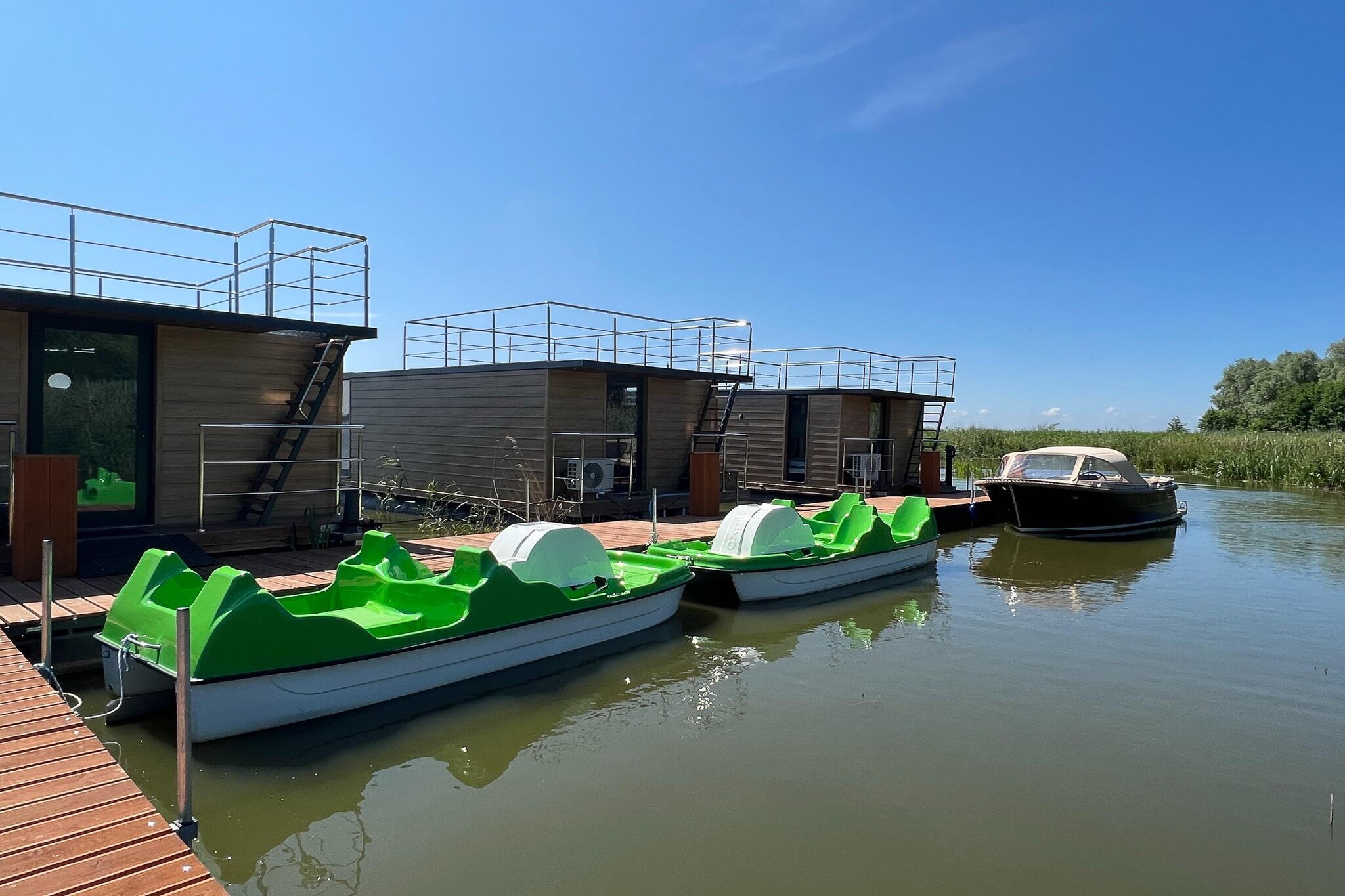 Houseboat is a charming, spacious cottage designed with comfort and relaxation in mind. Its unique location on the water creates an unforgettable atmosphere and allows you to enjoy the peace of nature.
The large terrace on the roof of the house is an ideal place to relax outdoors. There is comfortable furniture where you can sit, relax and enjoy the beautiful views.
On the ground floor of the house there is a covered terrace with garden furniture, which offers additional space for relaxation and outdoor meetings. It's the perfect place for a morning coffee or an evening drink overlooking the water.
The house on the water is equipped with air conditioning and heating, which makes it comfortable and friendly for every season. Regardless of the weather, you can enjoy a pleasant temperature inside the cottage. 

The recreation center is beautifully located directly on Lake Jamno, about 200 meters from the sea, right next to the forest. The plot is covered with old trees, 
Guests have at their disposal a free parking lot, a playground for children, a place to light a bonfire, a grocery store, a motorboat cruise and a rental of: bicycles, water bikes, electric scooters, water bikes and a barbecue.
There are shops, restaurants and bars nearby. 

Łazy is a small and quiet seaside town, surrounded by lakes and forests, a perfect place for people looking for relaxation surrounded by nature and away from the crowds. Surrounded by the calm sea, fresh air and breathtaking landscapes, guests can fully relax and break away from everyday worries. Numerous bicycle paths allow guests to explore the area on two wheels, enjoying the beauty of nature.