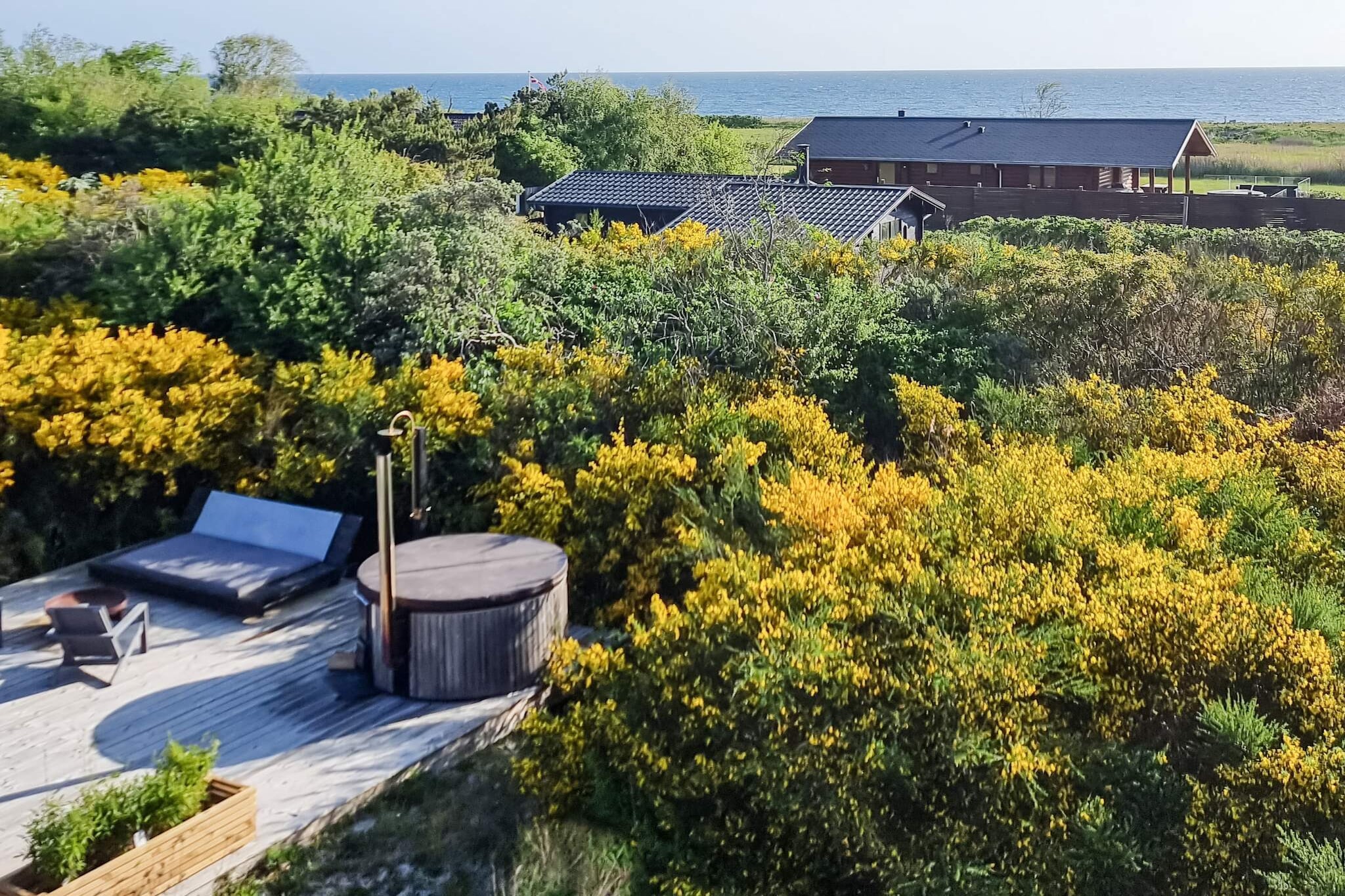 This unique architect-designed vacation home is located in the picturesque landscape of Sjællands Odde on a beautiful natural plot and exudes stylish elegance with its clean lines. Here, friends or couples can enjoy a very special experience in the open, multifunctional space with complete interior furnishings. The heart of the house is centered around the stylish, 3-sided fireplace insert. Here, a classic New York atmosphere prevails with large factory windows that provide fantastic light and a particularly rugged look. Enjoy the beautiful view of the Kattegat from the large double bed in the attic with a good podcast in your ears, or spend a quiet moment in the bathtub in the bedroom with the doors open to the garden. The entire house exudes exclusivity with details in marble, golden colors, and plywood-clad walls and ceilings. Outside, you will find the beautiful, sunny wooden terrace that winds around the house. Prepare a wonderful dinner on the barbecue in the open air in the delicious outdoor kitchen or enjoy the long summer evenings in the hot tub. There is also space on the terrace to light a cozy fire while a beautiful sunset sets the evening sky ablaze. No rentals to youth groups!A refundable deposit might be charged closer to your check-in date. The security deposit ensures a smooth stay and covers any additional services or consumption charges.This deposit covers utilities consumed during your stay and any additional services that may be taken.The final amount will be adjusted based on actual meter readings, actual usage of extra services, and any remaining balance will be refunded within 21 days after checkout.This deposit simply acts as a prepayment for charges that  you would anyways pay for, ensuring a seamless stay and check-out experience.