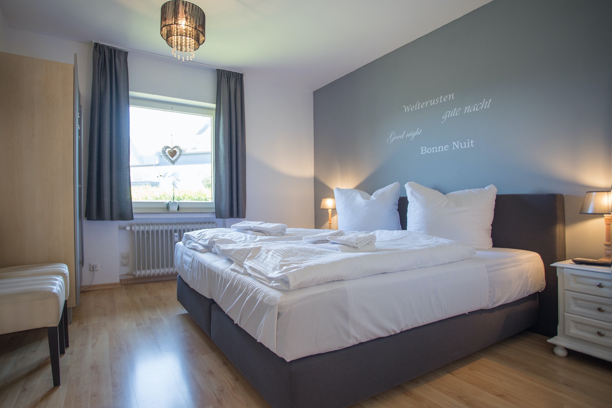 Ground floor: (Living room(TV(flatscreen), dining table, seating area), open kitchen(electric kettle, toaster, cooker, coffee machine(filter, pads), combination microwave, dishwasher, fridge(+ freezer)), bedroom(double bed(boxspring, 180 x 200 cm), TV), bedroom(double bed(140 x 200 cm)), bathroom(bath tub, shower, washbasin, toilet, hairdryer), Landing)\n\nstorage, cot, washing machine, balcony, garden furniture, parking, high chair