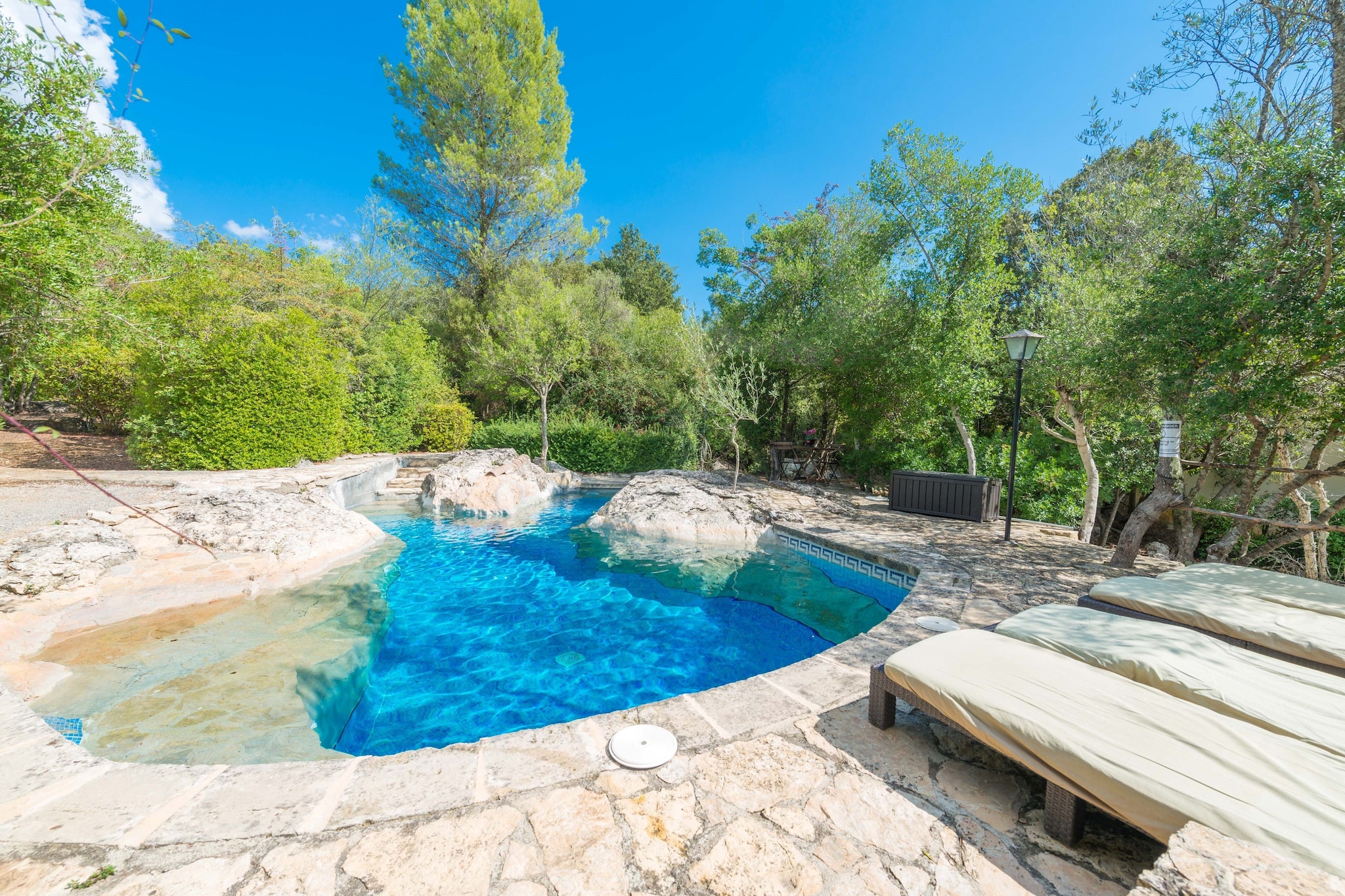 The exterior of the property is simply enchanting. The swimming pool —partly carved into the natural rock— is one of its most captivating features: a serene corner that invites you to relax and unwind. Measuring 6 x 5 metres with a maximum depth of 1.80 metres, it offers a refreshing dip in the heart of nature. A spacious, furnished terrace provides the ideal setting for outdoor meals or quiet reading moments beneath the shade of the trees. An electric barbecue is available (as the use of fire is prohibited during the summer months). Upon arrival, guests will be greeted by Miquelet, a friendly donkey who lives on the neighbouring grounds. Thanks to its secluded location and surrounding woodland, the property guarantees complete privacy — the perfect spot for an authentic and tranquil rural escape.
Inside, the house retains the cosy character of traditional Mallorcan country homes, with stone walls, exposed wooden beams, and warm, functional décor. The inviting living room features satellite TV and central heating, making it a comfortable choice even during the cooler months. The open-plan kitchen, equipped with a ceramic hob, blends seamlessly with the dining area and includes everything you need to prepare home-cooked meals. There are two bedrooms — one with a double bed and the other with two single beds — both with ceiling fans and heating. The bathroom includes a shower, and all spaces are designed to offer comfort in a simple, natural setting. For added convenience, the house provides a washing machine, iron, and ironing board, as well as a cot and high chair for families travelling with a baby.
The winding, narrow road leading to the house sets the tone for the natural surroundings and the tranquillity that envelop it, where even mobile reception is basic, enhancing the feeling of being disconnected. Its relatively central location makes it easy to explore different parts of the island. The nearest sandy beach, Puerto de Pollença, is about 19 km from the house. It is a fine sandy beach that slopes gently into the sea. The surrounding mountains provide a beautiful contrast with the sea. Pollença can be reached in around 20 minutes by car and was once popular with painters and artists. This influence can still be felt today and gives the town a unique character. Don’t forget to visit the Romanesque Bridge, as well as the small church on the hill of “Calvari”. Consult the advertiser for possible charges. Pets are not allowed. The holding of events is forbidden. There is exterior parking for 2 cars.
Distances
Beach: 17.3 km - Puerto de Alcúdia
Airport: 53.4 km - Son Sant Joan
Golf course: 7 km - Pollença
Town: 6 km - Campanet
Train station: 11.2 km - Sa Pobla
Bus stop: 11 km - Sa Pobla
Ferry: 18 km - Alcúdia
Hospital: 7 km - Inca
Tourist license: ETV/25Single Rental Registry: ESFCTU0000070220000040410000000000000000000000ETV/255Homerti - Central de Reservas CR/33