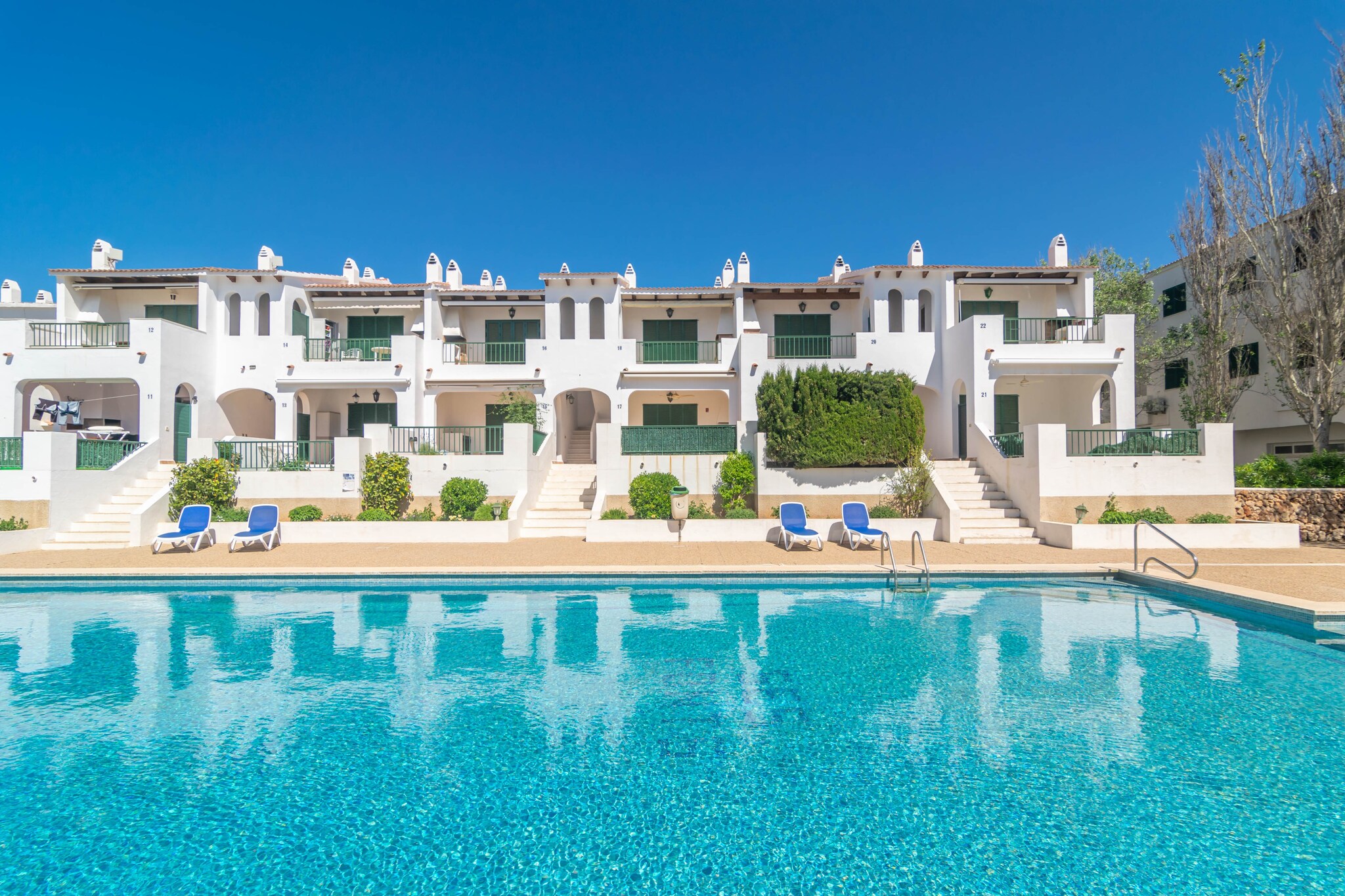 The outside of the apartment complex will transmit you the authentic Menorcan essence. Strolling through its beautiful gardens you will come to a shared chlorine swimming pool with a children's area. It measures 20x10m and its depth varies between 0.5m and 2m. Once in the flat, you will be able to enjoy a terrace where you can relax in the sun or have something to eat with your family and friends. Due to its location in a building, the flat has direct neighbours.
The interior of the flat is designed for your relaxation. The living-dining room has AC and TV and is open to the kitchen, which is equipped with everything you need to prepare delicious meals. There is also a washing machine, iron and ironing board in the house. When it is time to sleep you will find 2 bedrooms, one with a double bed and one with two single beds. There is also a bathroom with shower. Please note that there is no cot or highchair.
The flat is located in a really privileged enclave, since many points of interest are close by. Thus, the magical villages of Es Mercadal and Fornells, which preserve all the Minorcan essence, are only a few kilometres away. Both are perfect for wandering among their whitewashed buildings and enjoying the best restaurants where you can enjoy typical dishes of the island's gastronomy. If you would like to learn a little more about Menorcan culture, you can visit the Talayotic settlement of Sa Torreta or visit the El Toro viewpoint, where you can enjoy panoramic views of Menorca. Finally, we recommend a visit to the Macar de Sa Llosa Natural Park, which offers an incomparable maritime setting where you can enjoy the Mediterranean in all its splendour. Consult the advertiser for possible charges. Pets are not allowed. The holding of events is forbidden. There is exterior parking for 1 cars.  Please note that the opening and closing dates of the communal pool are subject to community regulations and may vary depending on the season, without prior notice. Updated information will be available upon your arrival.
Distances
Beach: 1.3 km - Arenal de Son Saura
Airport: 26.2 km - Maó
Golf course: 2.2 km - Son Parc
Town: 12.3 km - Fornells
Train station: 0 km
Bus stop: 0.35 km - Carrer Major
Ferry: 21.4 km - Maó
Hospital: 22.4 km - Hospital General Mateu Orfila
Tourist license: ET2610MESingle Rental Registry: ESFCTU00000701300004383300000000000000000000ET261ME8There's a mandatory tourist tax in Balearic Islands, called Ecotasa. All guests, except people under 16 years, have to pay this tax. The amount varies between 0.55€/night and guest during the low season and 2.2€/night and guest during  the high season .The tax is reduced by half from the 9th day for your stay.
