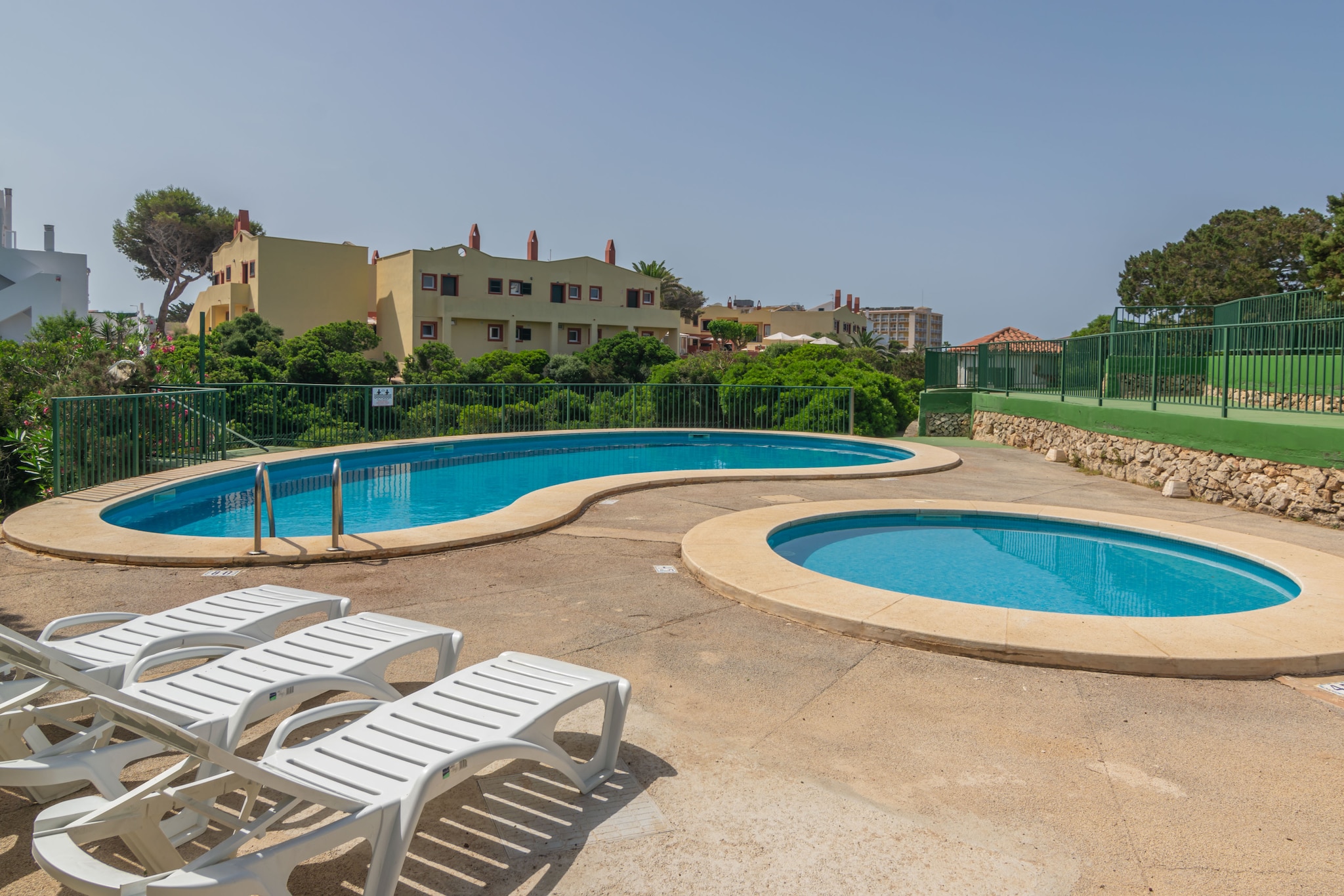The well-kept urbanization offers wonderful garden areas with communal loungers around the refreshing shared chlorine pool that measures 10 x 4 meters and has a depth that ranges between 0.85 and 1.45 meters. The little ones will enjoy the children's pool that measures 3 meters in diameter with a depth of 0.45 meters. The apartment is located on the ground floor and offers a nice furnished terrace to enjoy your meals alfresco.
Once inside we find a cozy dining room that leads to the kitchen through an arch. The kitchen is equipped with a ceramic hob and offers the basic equipment for cooking during your vacation. There is also a washing machine, an iron and an ironing board. The 4 guests can rest in 2 bedrooms with 2 single beds and a fan each. The apartment's bathroom has a bathtub. Lastly, if you are travelling with your baby we can provide you with a cot and a high chair.
The Cala en Blanes area is a quiet and family friendly tourist destination where you will find the basic services for your stay and nearby public transport stops to visit Ciutadella and other wonderful places on the island. The closest beach is the Cales Piques cove. Cala en Forcat and Cala en Brut are other coves with turquoise waters that can be reached on foot.
There is community outdoor parking without an assigned space.
The swimming pool is open from 10 am to 8 pm and from June to September. Consult the advertiser for possible charges. Pets are not allowed. The holding of events is forbidden. Please note that the opening and closing dates of the communal pool are subject to community regulations and may vary depending on the season, without prior notice. Updated information will be available upon your arrival.
Distances
Beach: 0.25 km - Cales Piques
Airport: 50 km - Maó
Golf course: 41.8 km - Golf Son Parc
Town: 1.3 km - Cala en Blanes
Train station: 0 km
Bus stop: 0.26 km - Pl. dels Dofins
Ferry: 8.2 km - Ciutadella
Hospital: 49.2 km - Hospital General Mateu Orfila
Tourist license: APM1872There's a mandatory tourist tax in Balearic Islands, called Ecotasa. All guests, except people under 16 years, have to pay this tax. The amount varies between 0.55€/night and guest during the low season and 2.2€/night and guest during  the high season .The tax is reduced by half from the 9th day for your stay.