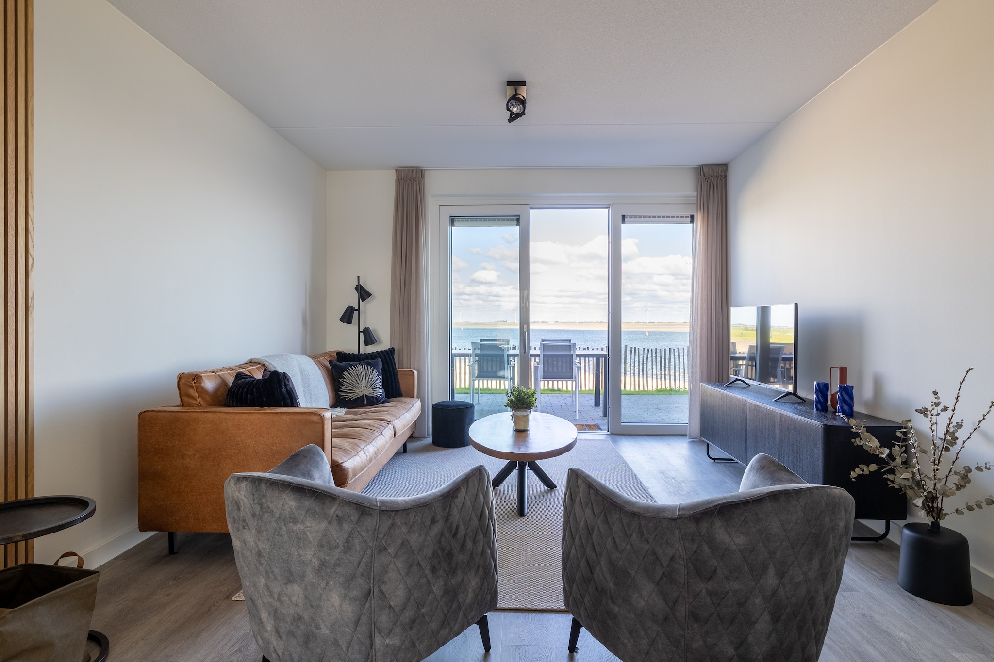 Wake up to breathtaking views of the harbor and Eastern Scheldt in this stunning apartment in Sint-Annaland. Boasting panoramic vistas, this spacious and luxurious accommodation offers the perfect combination of comfort, tranquility, and modern amenities. Situated in a peaceful location yet close to everything you need, itâ€™s an ideal base for a relaxing holiday with family or friends. The bright living room is designed for relaxation, featuring a comfortable seating area where you can enjoy the spectacular views. French doors open to a fully enclosed terrace, perfect for enjoying meals outdoors or unwinding with a drink while watching the sunset. Just beyond the gate, you have direct access to a small beach for a refreshing walk along the water.

Located in Sint-Annaland on the island of Tholen, this apartment offers easy access to scenic landscapes, water sports, and cultural sights. Explore the village, cycle through the countryside, or enjoy windsurfing and kitesurfing in the Eastern Scheldt. With its rich history and natural beauty, Sint-Annaland is the perfect place for an unforgettable Zeeland getaway.

The modern kitchen is well-equipped with a cooktop, combi-microwave, dishwasher, fridge, freezer, and small appliances such as a toaster and citrus juicer. Enjoy meals at the oval dining table, or step out to the spacious balcony to lounge while overlooking the harbor. Two bedrooms, each with a double bed and incredible views, ensure a restful nightâ€™s sleep. The stylish bathroom features a walk-in shower, and an additional separate toilet adds convenience. The apartment includes bike storage, e-bike charging points, and 2 reserved parking spaces.