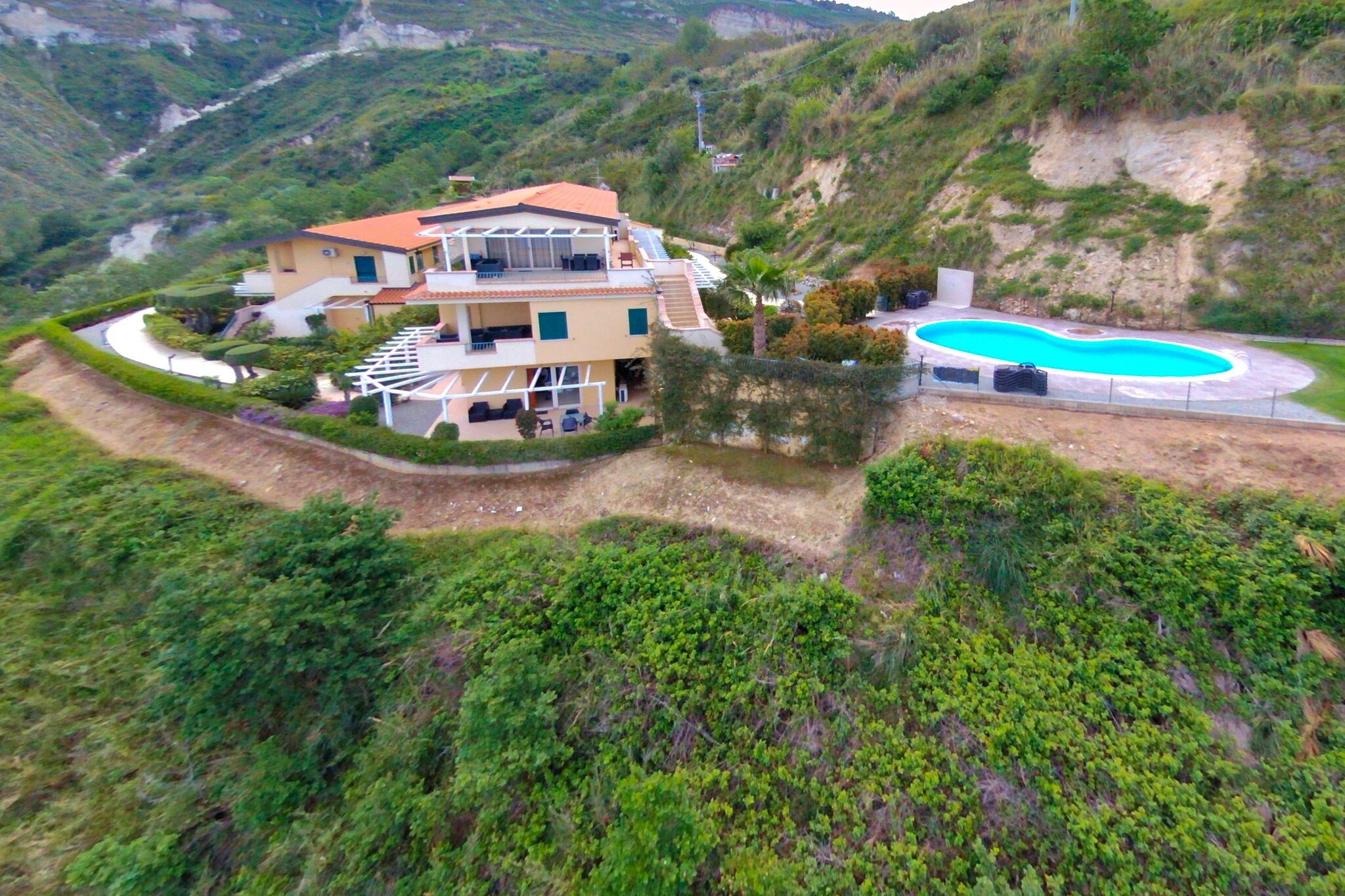 An optional utilities and service fee of EUR 70,00 will be charged before your arrival. Details are given below.<br> Set on a hill between Parghelia and Tropea in Italy, this holiday apartment with 2 bedrooms can host a family of 4. It has a swimming pool to unwind and deckchairs to lounge. Offering stunning views over the Tyrrhenian Sea, the apartment is set in a brilliant location. You can relax by the sea or engage in your favorite water sports activities. You can also hit the idyllic town of Tropea that's 5 km away and enjoy a boat trip across the coast to the Aeolian Islands and visit Vulcano, Lipari or Stromboli.Santa Maria dell'Isola, Creazioni Artistiche Il Faro, and Corso Vittorio Emmanuele are also worth-a-visit. In free time, you can hit nearby shops, general stores, and restaurants, all within 1000 m from this house. Don't forget to visit the town center of Vibo Valentia located just 20 km away.
Only guests with a confirmed reservation are permitted to enter the park, as indicated by the signage outside the gate. This holiday accommodation has private parking. It has remote controlled entrance gates to offer security and privacy. The airport of Lamezia Terme is 50 km away. Note: The park is located on a mountain and is only accessible by car. Also, the swimming pool is opened from end of April to the end of October. <br><b> Optional Utilities & Service Package </b><br><b> An optional utilities and service package of EUR 70,00 </b> can be selected prior to your arrival. You will receive a separate communication with the payment link should you wish to include it.<br>This package ensures a seamless stay and conveniently covers services such as final cleaning, utility consumption, service support, and protection against minor damages or incidental costs during your stay.<br>Guests who prefer may manage these services independently, provided the property is returned in good order at check-out.