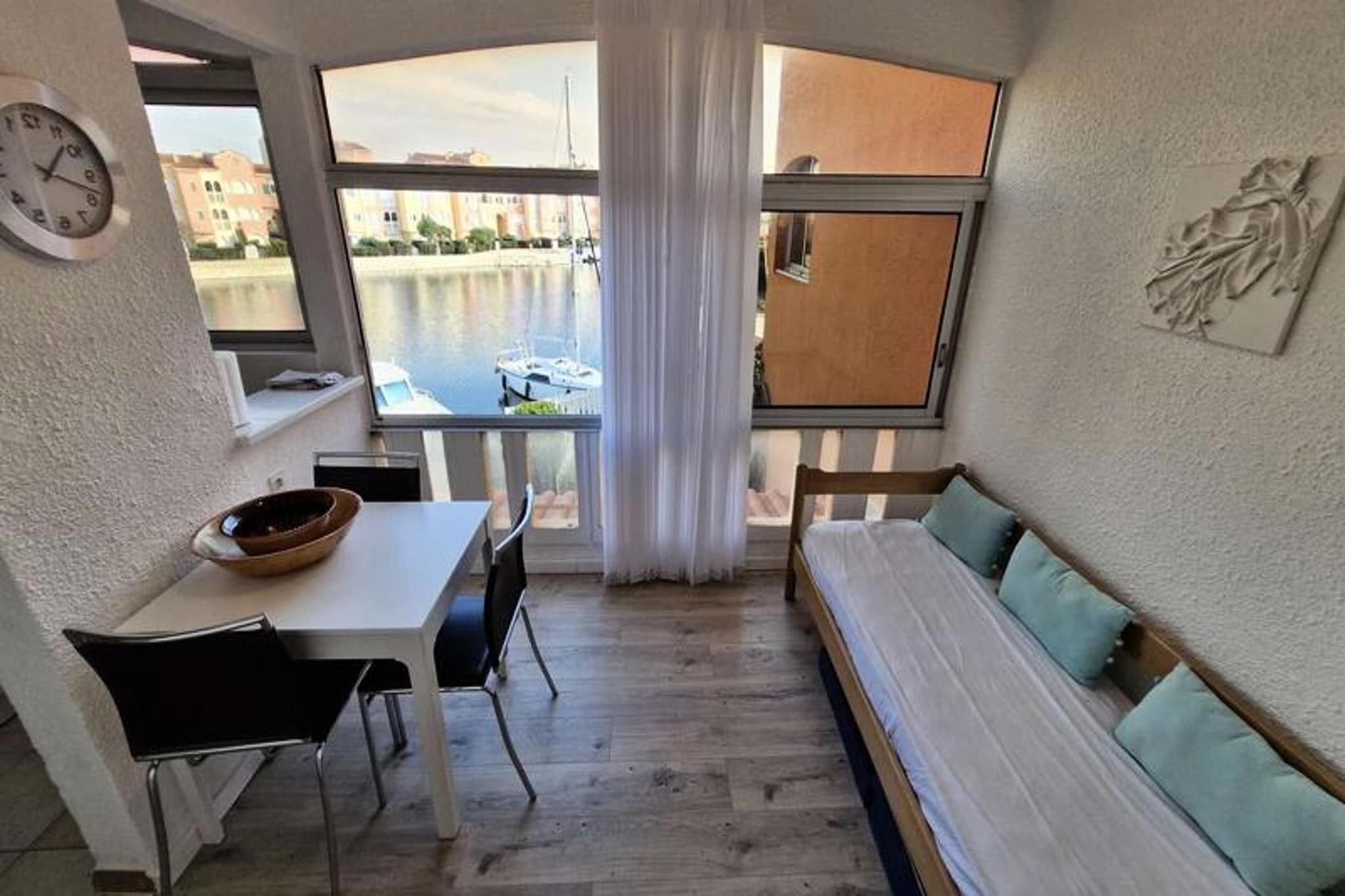 This studio apartment, designed to accommodate up to three people, offers a comfortable retreat with a beautiful view of the channel and the marine lake. It features a living room with a two-person convertible sofa, as well as a loggia with a single bed exclusively for a child. The apartment is equipped with essential amenities including air conditioning, ceramic hob, oven, fridge-freezer, and a washing machine. It is located on the first floor of a residence with no elevator, providing a quiet and cozy atmosphere.

Situated just 2 km from the beach, the property is conveniently close to local shops, with a market only 300 meters away. Guests can easily explore nearby cafes and restaurants, offering a range of dining options. The location also provides access to scenic outdoor activities along the coast, perfect for those seeking relaxation or adventure.

The apartment is equipped with a kitchenette for preparing meals, and the loggia offers additional space to enjoy the surroundings. The bathroom is equipped with basic amenities, and the collective parking at the residence ensures convenient access. During warmer months, guests can enjoy the condominium swimming pools, though please note that access may be restricted due to water conservation measures.