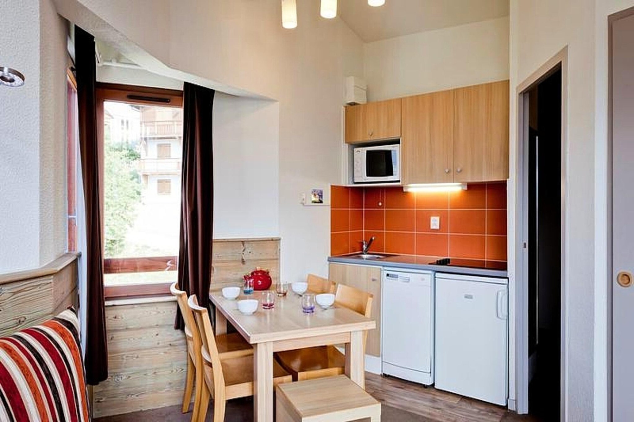 This charming apartment is located in the heart of La Tania, perfect for a family or small group seeking a comfortable stay. The accommodation features one double bedroom, a living area with a convertible sofa that sleeps two, and a private bathroom with a toilet. The property is not pet-friendly and offers essential amenities such as linen (included), and an option for towel rentals at an additional charge. The unit is on the second floor and offers a balcony with a stunning mountain view, perfect for enjoying the peaceful surroundings. A covered parking space is available 30 meters from the residence, ensuring convenience for guests with a vehicle.
Located at the foot of the slopes, this apartment offers ski-in, ski-out access to La Tania’s pistes. The village center, with restaurants, cafes, and shops, is just steps away. Guests can enjoy dining options, explore the Courchevel La Tania forest, or try activities like paragliding, canyoning, and hiking in the Vanoise Massif..
The apartment features an open kitchen with a stovetop, oven, and fridge, along with a comfortable living area and dining space. Wi-Fi is available for an additional cost, and daily cleaning or towel services can be requested at reception. Ideally located near ski slopes and village amenities, this apartment offers a relaxing stay in La Tania.