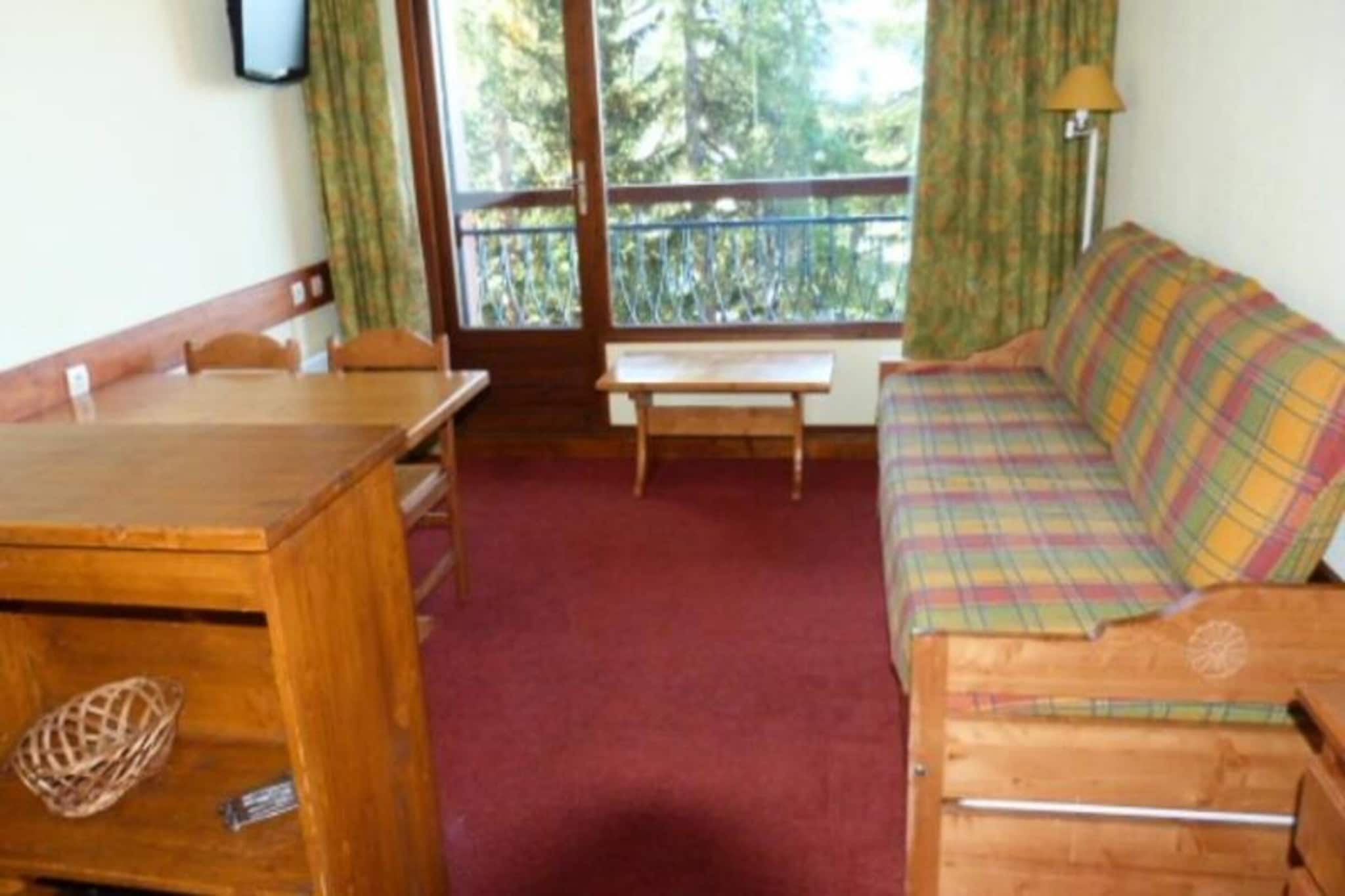 This two-room apartment, located in the Charmettoger village, comfortably accommodates up to five guests. It features a living room with a pull-out sofa bed and an 80x190cm folding bed, plus a bedroom with two 80x190cm single beds. Pets are allowed. The apartment is on the 5th floor of a building with a lift and offers a south-west facing balcony with valley views. A ski locker is provided.
Situated 70 meters from the "Charmettoger" blue slope and 100 meters from the "Jardin Alpin" chairlift, this apartment offers easy access to skiing. A free shuttle stop is 100 meters away, running every 20 minutes in winter and hourly in summer. The nearest supermarket and ESF ski school are a 10-minute walk away in Villards village. The Tourist Office and medical office are a 15-minute walk or shuttle ride away. In summer, an outdoor swimming pool is available.
The apartment includes a bathroom with a bathtub and a separate toilet. The open-plan kitchen is fully equipped with a ceramic hob, refrigerator, toaster, kettle, coffee maker, dishwasher, and microwave. A television is provided in the living room. Covered parking is available for an additional cost, subject to availability. Duvets are provided, but bed linen is not included.