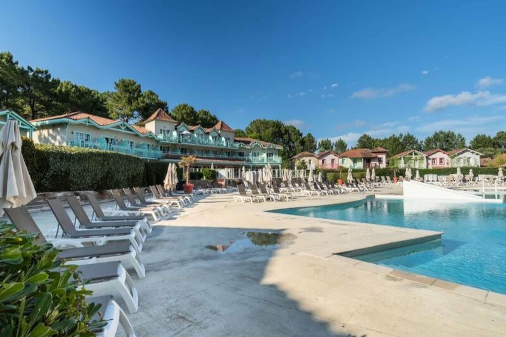 Nestled amidst a 4.6-hectare pine forest, this charming two-bedroom holiday home in Lacanau Les Pins offers a relaxing retreat just 2km from the beach. Part of Village Lacanau, the property boasts colorful architecture characteristic of the Landes region. Guests can enjoy free access to the on-site aquatic area (swimming pool + paddling pool), a beach volleyball court, a multi-sport court, and more. Bicy'cool offers bike rentals and Evolution 2 provides activities for all ages, from yoga to swimming classes. 

The area is a paradise for cyclists, with long stretches of beaches ideal for surfing. Lacanau town itself is also within easy reach. For an additional fee, guests can access the spa area at a partner facility, which includes discounts on massages and a free glass of champagne with dinner.

This tastefully renovated duplex features a living room with a sofa bed, a well-equipped kitchen, two bedrooms, two bathrooms, a separate toilet, a terrace, a garden, and parking. The south-facing property offers beautiful forest views. The master bedroom has a double bed, the second bedroom has two single beds, and a cabin area with bunk beds provides additional sleeping space. In-bathroom amenities include a shower, bathtub, electric towel dryer, and hairdryer.  Please note that Wi-Fi, bed linens, towels, and end-of-stay cleaning are all available for an additional charge.