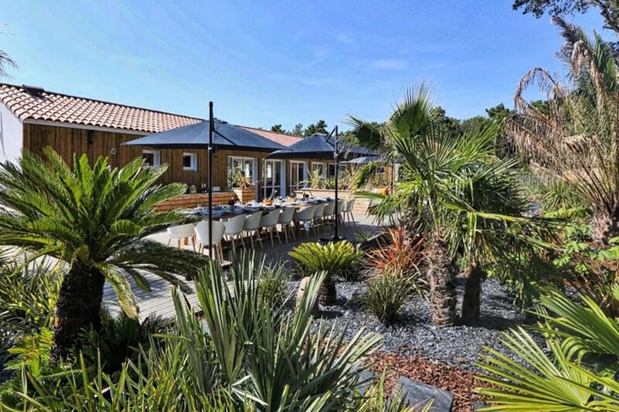 This spacious 250m² villa, decorated in a Latin American style, offers a relaxing retreat for up to 14 people. It has 7 bedrooms with 4 double beds and 6 single beds (convertible into 3 doubles), 2 bathrooms, and 2 separate toilets. Pets under 25 kg are allowed for an additional fee. Amenities include a TV with TNT channels, a washing machine, hairdryer, and ironing facilities. The large private terrace features garden furniture and two spas (swimming and jacuzzi), ensuring a comfortable outdoor space for guests.
Located in the Pays-de-Monts national forest, the villa is just minutes from the beach. Explore the area via cycling paths or enjoy the local attractions nearby. The tranquil setting provides a perfect environment for relaxation, while the beach and surrounding areas offer opportunities for outdoor activities and exploration.
The villa features a fully equipped kitchen with modern appliances, including an oven, fridge-freezer, microwave, and Krups coffee maker. The spacious living room provides a comfortable place to unwind. Additional amenities include a private beach volleyball court, barbecue, and Aquabike for recreation.