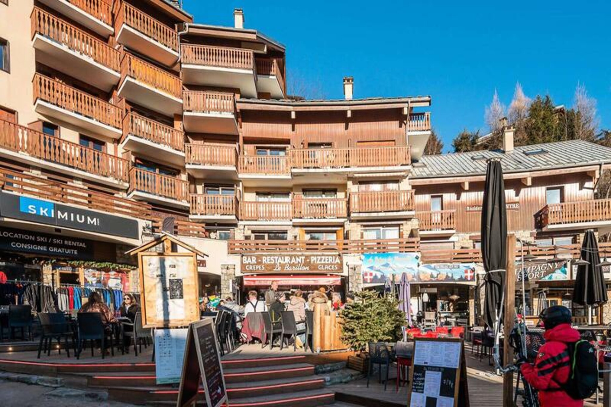 This cozy apartment accommodates up to 6 guests and offers a comfortable retreat with modern amenities in the heart of the village. It includes a bedroom with a double bed, a mountain corner with bunk beds, and a living area with two single beds, all with duvets for added comfort. Guests can enjoy stunning views from the south-facing balcony, overlooking the village square and surrounding mountains. Non-smoking and pet-free, it’s ideal for those seeking a peaceful stay.
Located in the village center, the residence provides easy access to attractions like the gondola and ESF (Ecole du Ski Français) for skiing. Shops on the ground floor offer convenience, while nearby cafes and restaurants provide a range of dining options. The area is perfect for outdoor activities such as skiing and hiking, with a local market offering fresh regional produce.
The apartment features a fully equipped kitchenette with an oven, microwave, fridge, electric hob, coffee maker, toaster, and kettle for self-catering. The bathroom includes a bathtub and separate toilet. Ski storage is available, and additional services like Wi-Fi, baby equipment, and end-of-stay cleaning are offered upon request.