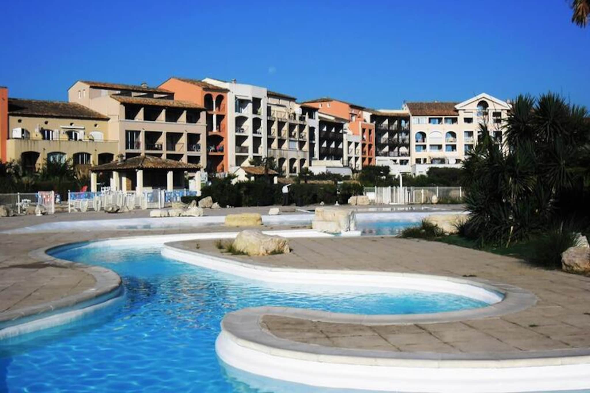 This pleasant 40m² apartment, located on the first floor (with elevator), comfortably accommodates up to four guests. It features a living room with a double sofa bed (160cm) and a bedroom with a double bed (160cm). The residence boasts direct beach access and a superb 650m² lagoon swimming pool (open from May 23 to the end of September), as well as two tennis courts. There is no on-site parking or WiFi. It is not mentioned whether pets are allowed.

Situated in Gassin, the apartment is conveniently located just 5km from Saint-Tropez and 12km from Sainte-Maxime. Shops are a mere 50m away, and the beaches are just 100m away. “Les Bateaux Verts” offer a regular shuttle service from Les Marines de Cogolin to Saint-Tropez and Sainte-Maxime.

The apartment includes an open fitted kitchen, a bathroom with a walk-in shower, and a separate WC. Amenities include an electric hob, dishwasher, refrigerator, coffee maker, toaster, and TV. There is no air conditioning. Bed linen and towels are available for rent. End-of-stay cleaning is compulsory and payable upon arrival. A €450 security deposit and tourist tax are payable on site. Heating is included.
