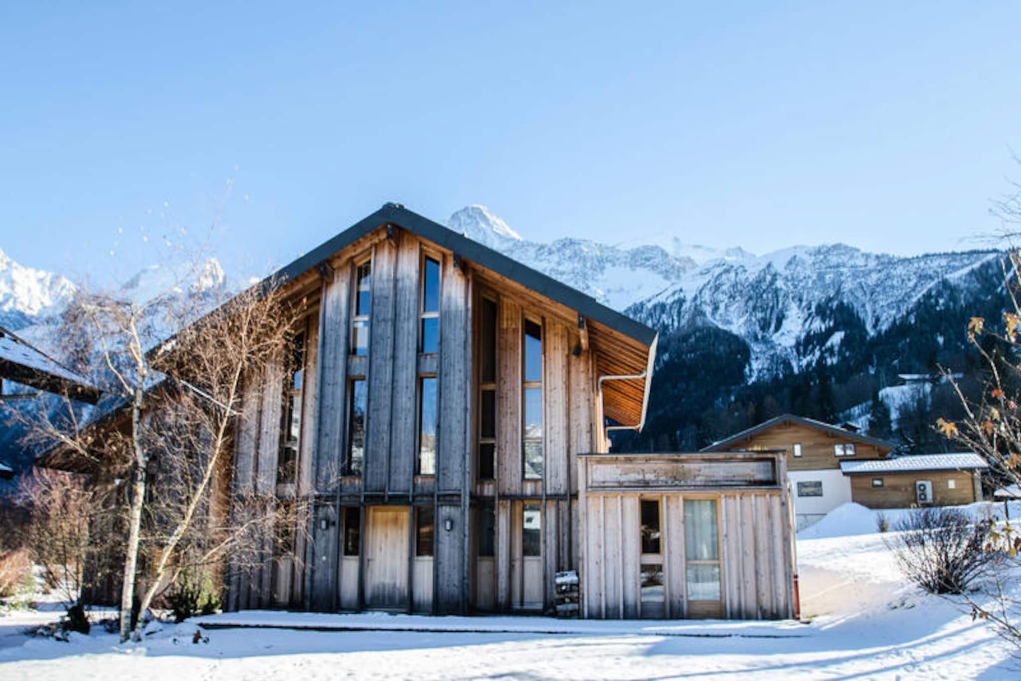 This beautiful 170m² contemporary chalet, classified as a 3-star property, offers comfortable accommodation for up to 12 people in its 6 spacious bedrooms. It features a cozy living room, dining area with a fireplace, and a library with satellite TV and Hi-Fi. The chalet is non-smoking and does not permit pets, ensuring a tranquil environment. The property also includes free Wi-Fi and a ski room. A deposit by credit card is required before arrival.
Located just 200 meters from the Prarion slopes, the chalet offers easy access to skiing and winter sports. The nearest bus stop, Le Prarion, is only 270 meters away, while the SNCF station in Les Houches is 2.5 km from the chalet. The charming town of Chamonix, known for its cafes, markets, and vibrant atmosphere, is 8.6 km away, providing guests with plenty of shopping and dining options.
The chalet’s fully equipped kitchen includes an induction hob, oven, microwave, dishwasher, and all essential utensils. It also offers a laundry room with a washing machine and dryer. Each bedroom features comfortable beds, and many offer stunning views of the Mont-Blanc range. Guests can also enjoy the 1500m² garden with a terrace, garden furniture, deckchairs, and a barbecue during the summer months.
