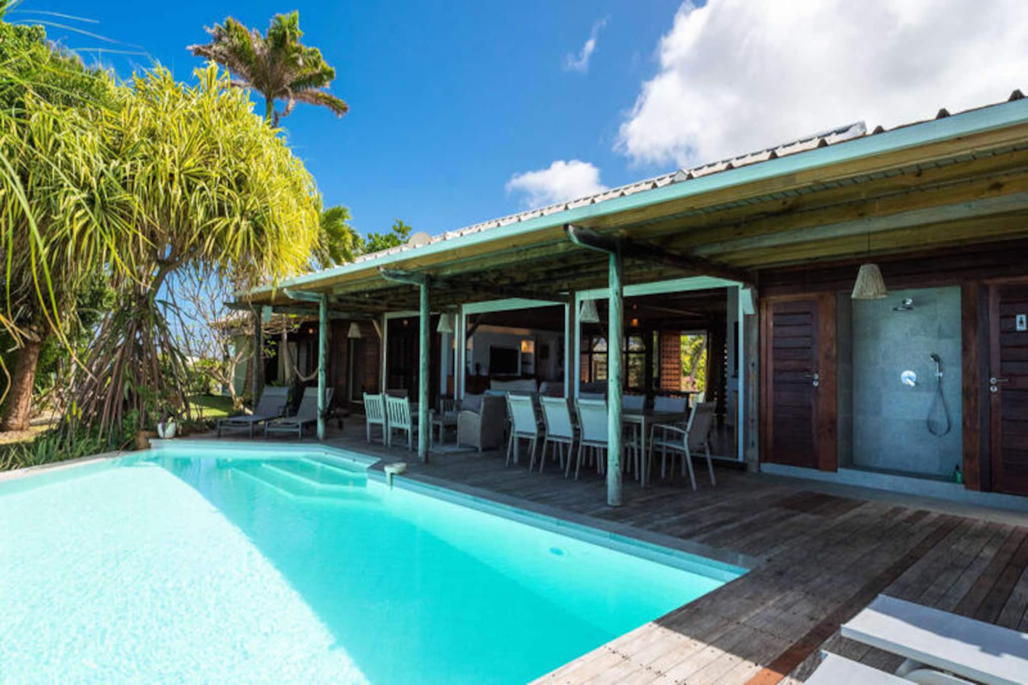 This beautiful 4-star villa combines exotic charm with modern amenities, offering four bedrooms and three shower rooms, accommodating up to eight guests. Each room boasts sea and palm tree views, with air conditioning in all rooms. The villa is perfect for relaxation, with a peaceful atmosphere and fresh organic eggs provided daily by friendly hens. Pets are not allowed, ensuring a tranquil environment.

Located in Moule, the villa is just a 3-minute walk from the Trade Winds beach and renowned surf spots. The vibrant Saint-François marina, featuring restaurants, shops, and a golf course, is only 15 minutes away. Guests can enjoy water sports like kiteboarding and wing-foil, or explore the local area, which offers all essential amenities including a supermarket, bakery, and pharmacy.

The villa features a fully equipped kitchen, perfect for cooking local meals, and a spacious terrace with shaded dining space. The emerald-colored pool, surrounded by lush vegetation, invites relaxation. Inside, the décor blends wood and art, creating a warm, welcoming atmosphere. The water reserve system ensures a reliable water supply throughout your stay.