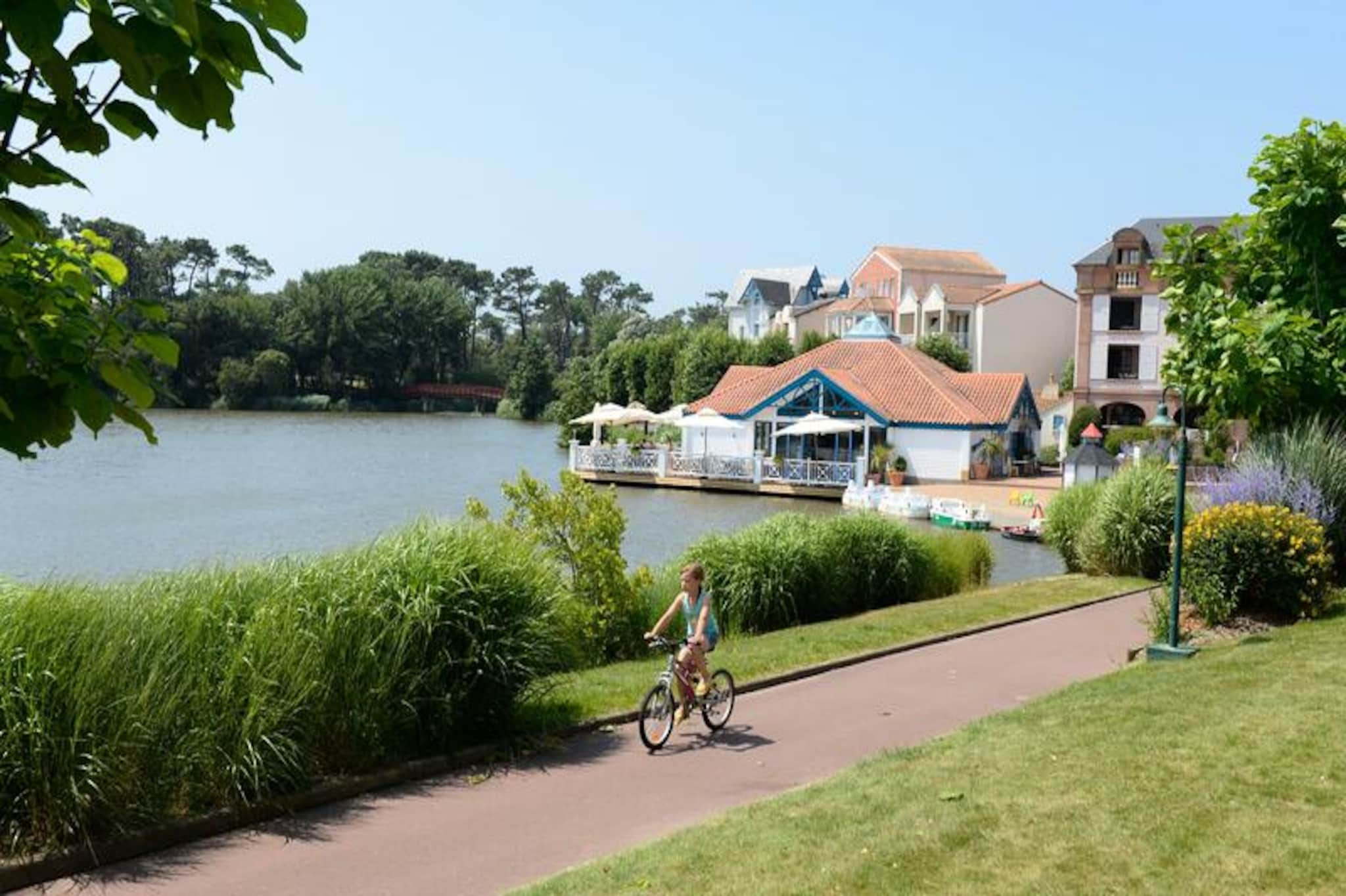 This apartment complex offers a variety of on-site amenities and activities for a relaxing vacation in Talmont-Saint-Hilaire, Vendée. The property is located within a 90-hectare estate surrounded by a pine forest and overlooking a lake. It features a pedestrian residence with shops, a pizzeria, bakery, and bar/ice cream parlor (independent businesses). The complex also boasts three swimming pools (open during specific dates) with slides and a paddling pool. Guests can enjoy additional entertainment options (for an extra charge) like tennis and mini golf, or explore two nearby 18-hole golf courses.
The apartment itself is a 25m² studio that comfortably sleeps five guests. It features a south-facing balcony with a sea view, a living room with a sofa bed for two and a trundle bed, an American-style kitchen, a cabin area with bunk beds, and a bathroom with a bathtub. The apartment is pet-friendly (with prior approval and additional fees).
Additional amenities and services available for a fee include Wi-Fi access, baby kit rental (crib and stroller), bed linen and towel rental, daily towel change, end-of-stay cleaning, and uncovered parking within the residence. The center pool is accessible to all guests from April 29th to September 15th. Lifeguards are present for the slide and pool only from July 1st to August 31st. Tourist tax varies depending on location and is free for guests under 18. A deposit is required upon check-in.