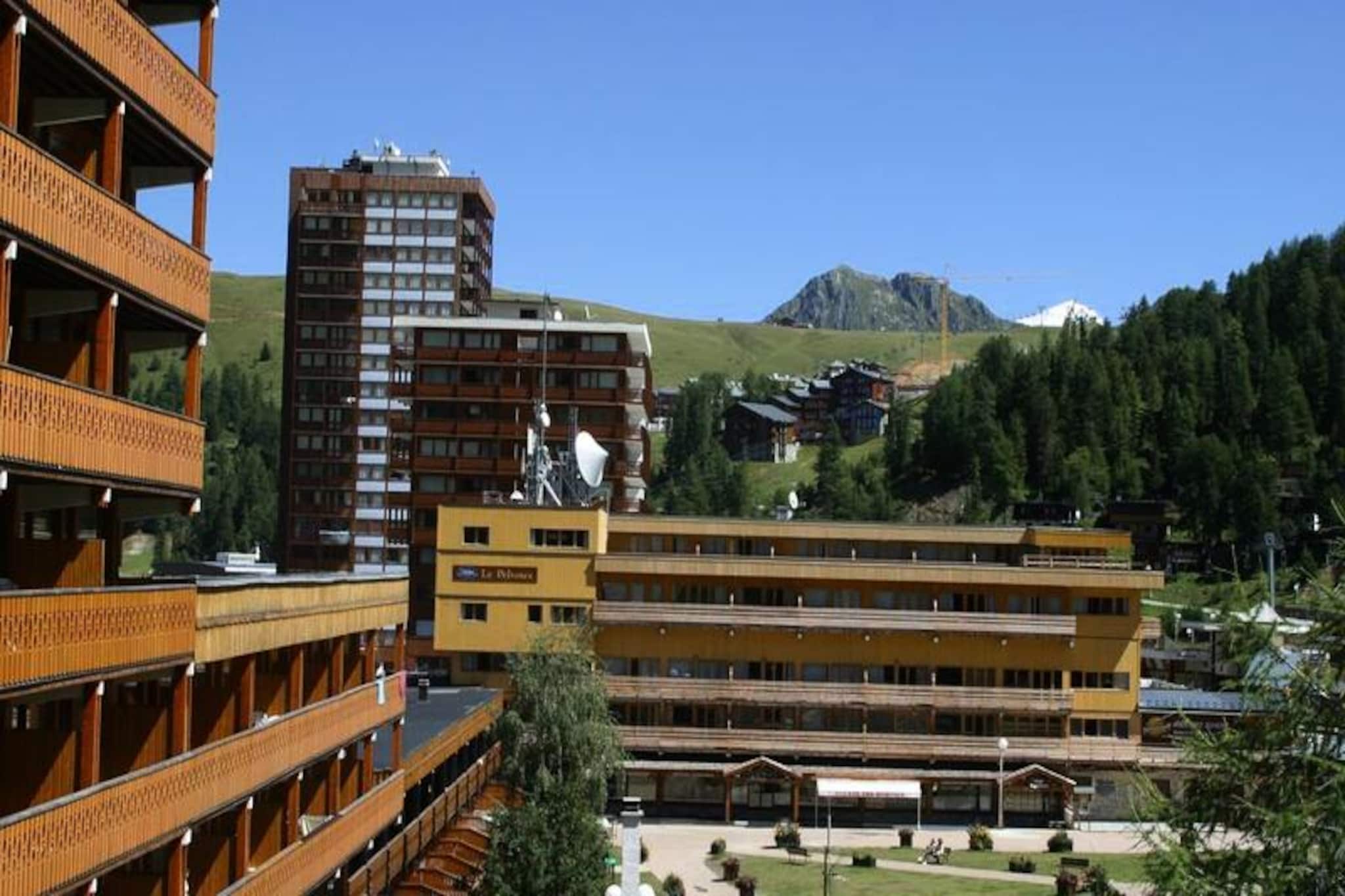 Enjoy your summer holidays in the heart of the Savoyard resort of Plagne Centre at Résidence Odalys Le Pelvoux. Ideally situated above the shopping mall, this residence offers easy access to shops, making it convenient for all your shopping needs during your stay. The residence boasts 28 apartments spread across three floors with an elevator, offering spacious accommodations in a typical Savoyard style with wooden facades and large balconies. The tranquil setting ensures a perfect retreat after a day of activities in the mountains.

In addition to a beautiful atmosphere, the residence provides a range of amenities to enhance your comfort, including a hammam and sauna for relaxation. For those looking to unwind, these facilities are the ideal way to rejuvenate. The residence is also conveniently located near the resort's many infrastructures, including a swimming pool in Plagne Bellecôte, perfect for your summer vacation in the mountains.

The apartments vary in size, accommodating between 8 to 10 people, and offer configurations with comfortable living areas, fully equipped kitchens, and bedrooms with double or single beds. Some apartments also include a mountain corner with additional bunk beds. The residence offers convenient services such as free Wi-Fi at the reception, baby kits, and optional covered parking for an additional charge. The perfect blend of comfort and convenience awaits you in the heart of the Tarentaise Valley.