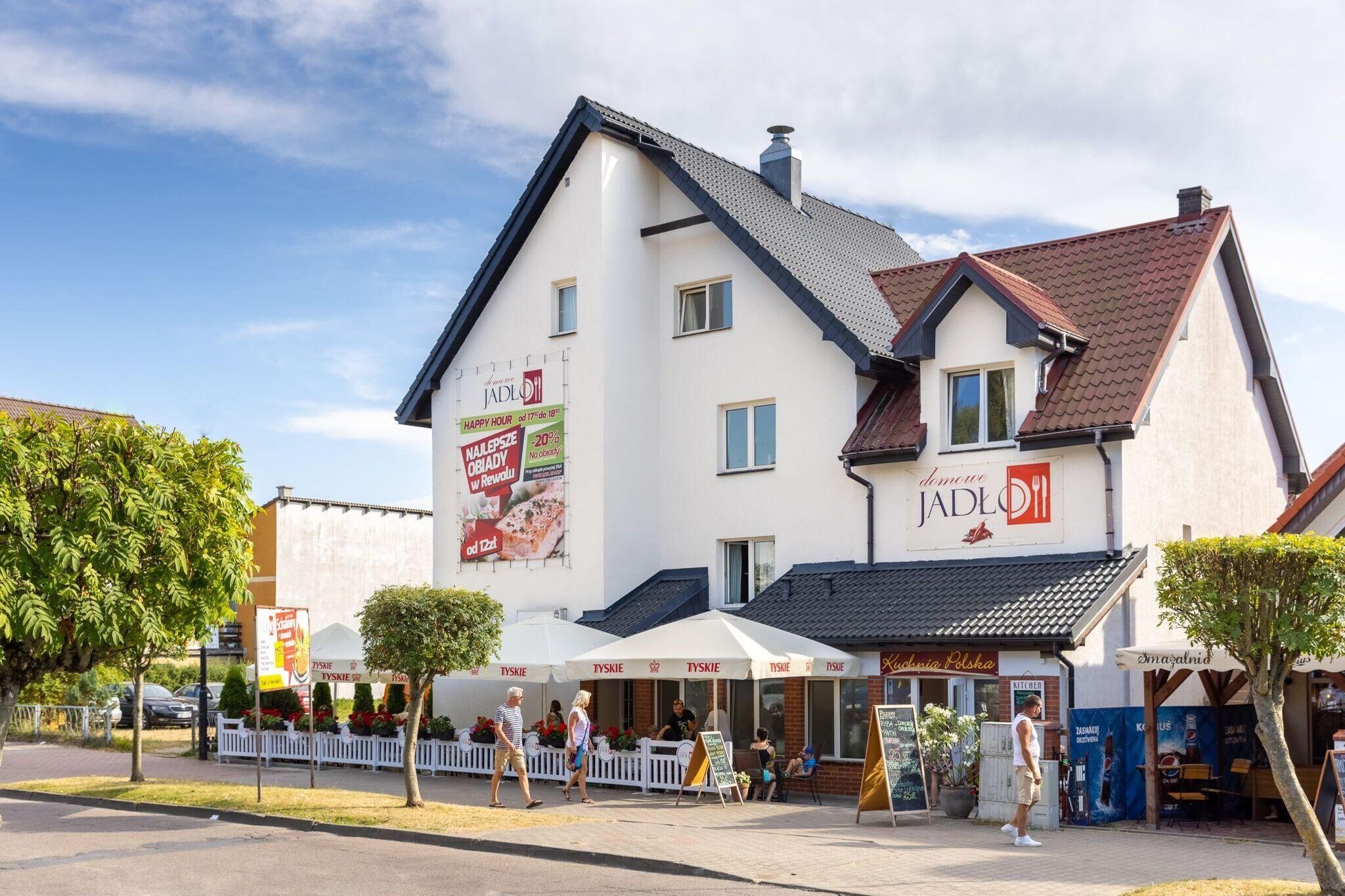 Intimate apartment building in a quiet area, within the center of the resort. 300 m to the beach. Restaurants, cafes, shops and all the attractions of the resort within a few steps.
Studio apartment on the first floor. It has a large, fenced terrace with a set of garden furniture. Guests have at their disposal an open space consisting of a living area (TV, double sofa bed, table), a well-equipped kitchen and a separate bedroom area with a comfortable double bed. Bathroom with shower. Central heating. Wireless internet is available.
On the fenced area next to the building there is a parking lot, a garden gazebo and a public grill. On the ground floor there is a cozy restaurant / bar. Buffet breakfasts are served here (included in the price of the stay). You can also order buffet dinners and lunches (several attractive offers every day).
The price of the stay includes: buffet breakfasts, bed linen, towels, electricity and water consumption, internet, parking, final cleaning. Baby cot and highchair on request.
Rewal is a charming seaside resort. It offers tourists a clean beach and unforgettable views from the seaside cliffs. There is a fishing base here, perfect as a background for souvenir photos. You absolutely have to see the symbol of the town: the mighty Rewal Whales on the promenade, at the viewing platform. Children will be delighted with a visit to the Whale Park, with real sea giants. A trip to the large Sandra aquapark in neighboring Pogorzelica will be fantastic entertainment for the whole family. The pride of the town is the renovated narrow-gauge railway, which can be used for a charming trip to neighboring resorts.