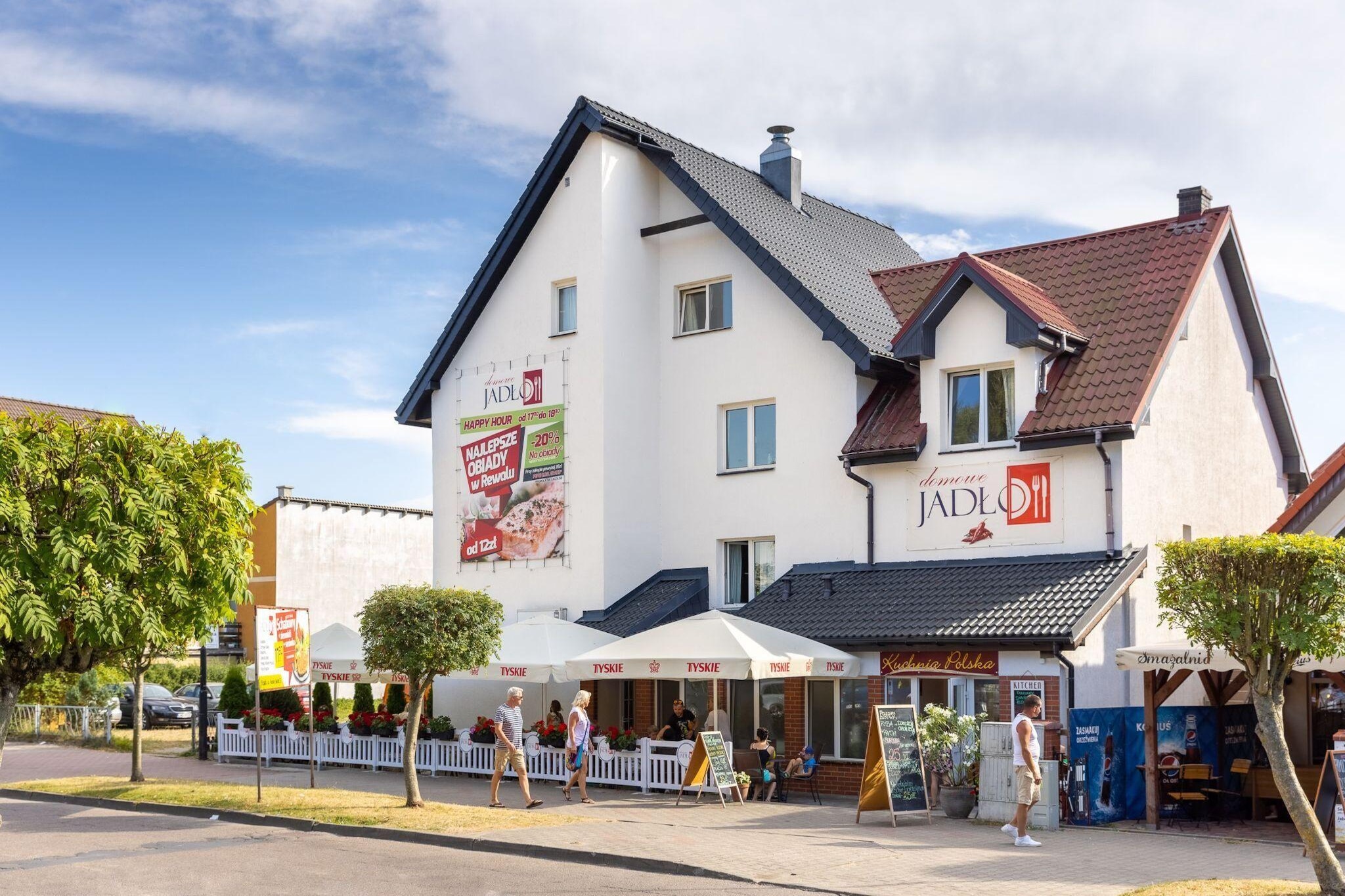 Intimate apartment building in a quiet area, within the center of the resort. 300 m to the beach. Restaurants, cafes, shops and all the attractions of the resort within a few steps.
Studio apartment on the first floor. It has a large, fenced terrace with a set of garden furniture. Guests have at their disposal an open space consisting of a living area (TV, double sofa bed, table), a well-equipped kitchen and a separate bedroom area with a comfortable double bed. Bathroom with shower. Central heating. Wireless internet is available.
On the fenced area next to the building there is a parking lot, a garden gazebo and a public grill. On the ground floor there is a cozy restaurant / bar. Buffet breakfasts are served here (included in the price of the stay). You can also order buffet dinners and lunches (several attractive offers every day).
The price of the stay includes: buffet breakfasts, bed linen, towels, electricity and water consumption, internet, parking, final cleaning. Baby cot and highchair on request.
Rewal is a charming seaside resort. It offers tourists a clean beach and unforgettable views from the seaside cliffs. There is a fishing base here, perfect as a background for souvenir photos. You absolutely have to see the symbol of the town: the mighty Rewal Whales on the promenade, at the viewing platform. Children will be delighted with a visit to the Whale Park, with real sea giants. A trip to the large Sandra aquapark in neighboring Pogorzelica will be fantastic entertainment for the whole family. The pride of the town is the renovated narrow-gauge railway, which can be used for a charming trip to neighboring resorts.