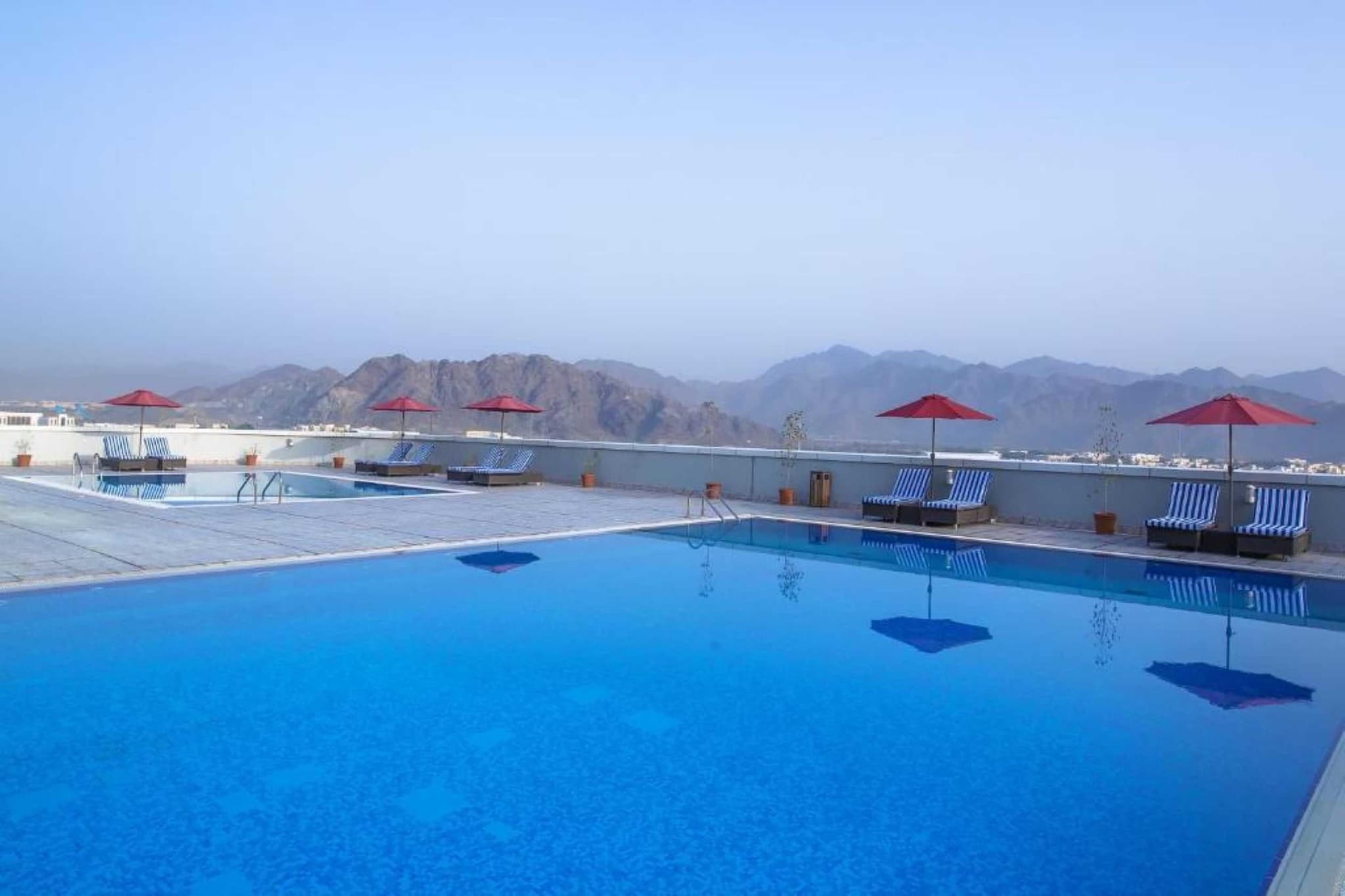 Escape to the calm of Cozy Queen Retreat, your serene sanctuary by the bay in Fujairah. With modern comforts, family-friendly spaces, and a peaceful ambiance, this stay is perfect for couples, solo travelers, and families looking to relax while staying connected to the heart of the city.

Top Highlights:
🏊 Two Rooftop Outdoor Pools – One for adults and one for kids, open year-round.

🌐 Complimentary High-Speed WiFi in all rooms and common areas.

🚗 Free Private Parking with valet and electric vehicle charging options.

👨‍👩‍👧‍👦 Family-Oriented & Accessible Rooms designed for every traveler.

💆 On-Site Spa & Wellness Centre featuring massages, sauna, and steam room.

🍽️ Two In-House Restaurants with international dishes and kid-friendly menus.

✈️ Airport Shuttle Service for added convenience.

💪 Well-Equipped Fitness Centre with personal trainers and classes.

🥐 Excellent Breakfast served daily, with in-room and dietary options available.

Tranquil Room Comforts:
Enjoy a restful stay in rooms featuring:

Private bathroom with shower, bath, bathrobe, slippers, and free toiletries

Extra-long beds, spacious wardrobe, and dressing area

Flat-screen TV, electric kettle, mini fridge, and scenic city or bay views

Family Fun & Leisure:
Designed for quality time with:

Indoor and outdoor play areas for children

Kids’ rooftop swimming pool

Billiards and table tennis (extra charge)

Business & Guest Services:
Whether you're working or unwinding:

Business centre and meeting facilities

24/7 reception, concierge, currency exchange, and express check-in

Daily housekeeping, laundry, and ironing services available

Relax & Recharge:
Let go of stress with:

Spa treatments, wellness packages, and Jacuzzi

Sauna, steam room, and rooftop loungers

Sun umbrellas and poolside comfort

Inclusive & Accessible:
Every guest is welcome with:

Accessible rooms and common areas

Elevators and bathrooms with grab rails

Languages Spoken:
Arabic, English, Hindi, and Filipino