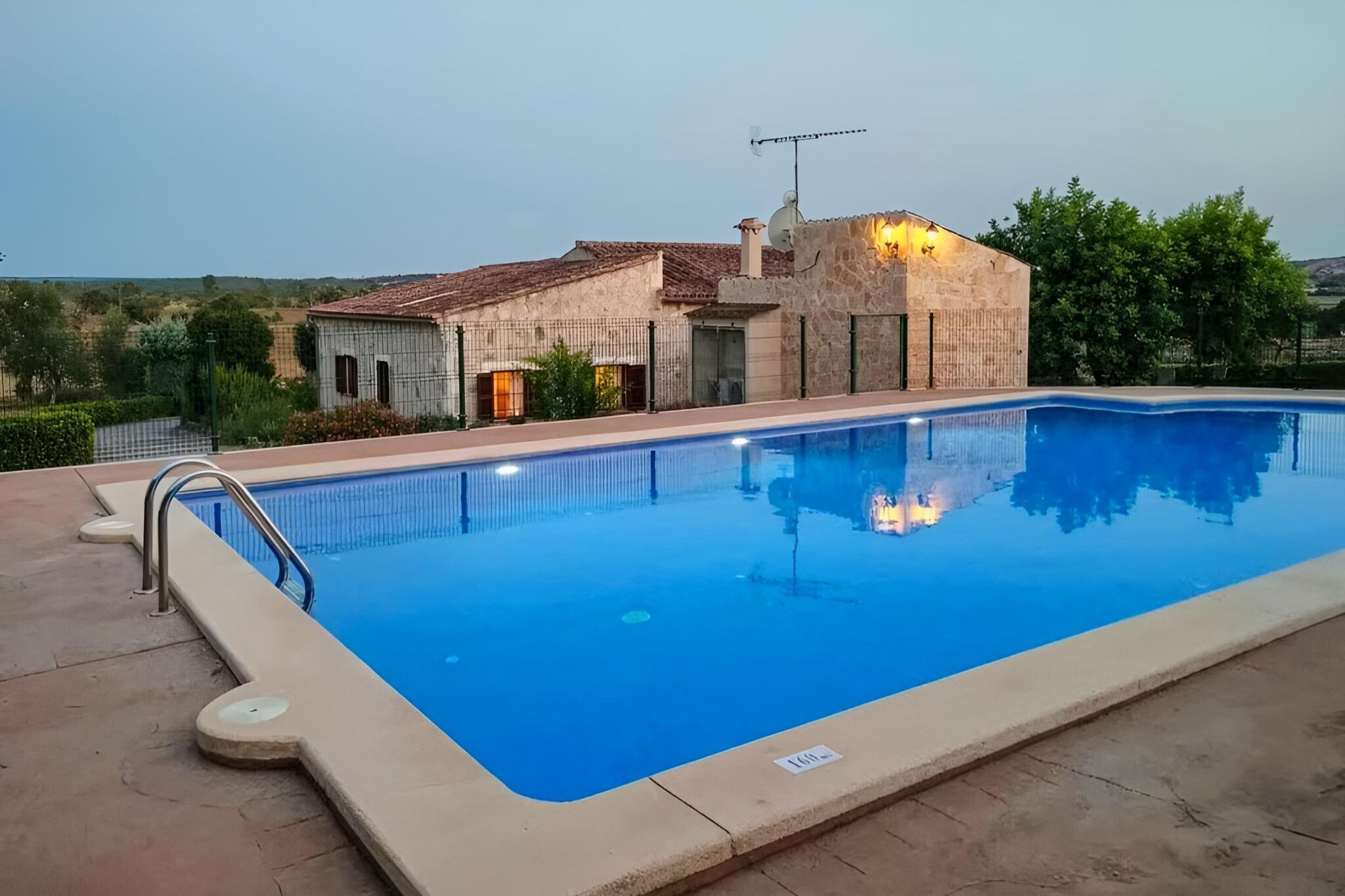 This holiday home estate is a wonderful retreat for families and groups of friends, perfectly balancing comfort, space, and a touch of nature. Just 10 minutes from the sandy beaches of Muro and Can Picafort, this single-level villa welcomes you with a bright living room, comfortable sofas, satellite TV, and a cool dining area – all fully air-conditioned. The modern kitchen, also air-conditioned and fully equipped, opens directly onto a shaded terrace where you can enjoy long meals together. With six cozy bedrooms, each with its own air conditioning, and three full bathrooms indoors plus an extra bathroom outside by the pool, the house is designed for both convenience and relaxation.
The heart of the estate is its beautiful outdoor space. A large saltwater pool (12m x 6m), safely fenced for children, invites you to cool off on warm days. Surrounded by greenery, hammocks under the trees, and inviting lounge corners, the garden feels like your own private oasis. The covered terrace with a spacious dining table and mobile barbecue sets the scene for relaxed summer evenings, while a ping-pong table and gym equipment provide entertainment and activity for all ages.
Thanks to its location, the home offers peace and privacy without sacrificing easy access. Within a short drive, you’ll find the lively villages of Maria and Santa Margalida with local shops, bars, and restaurants, while the golden beaches of the north coast are just minutes away. Whether you’re seeking lazy days by the pool, fun activities with the kids, or adventures around Mallorca, this estate is the perfect home base for an unforgettable holiday.